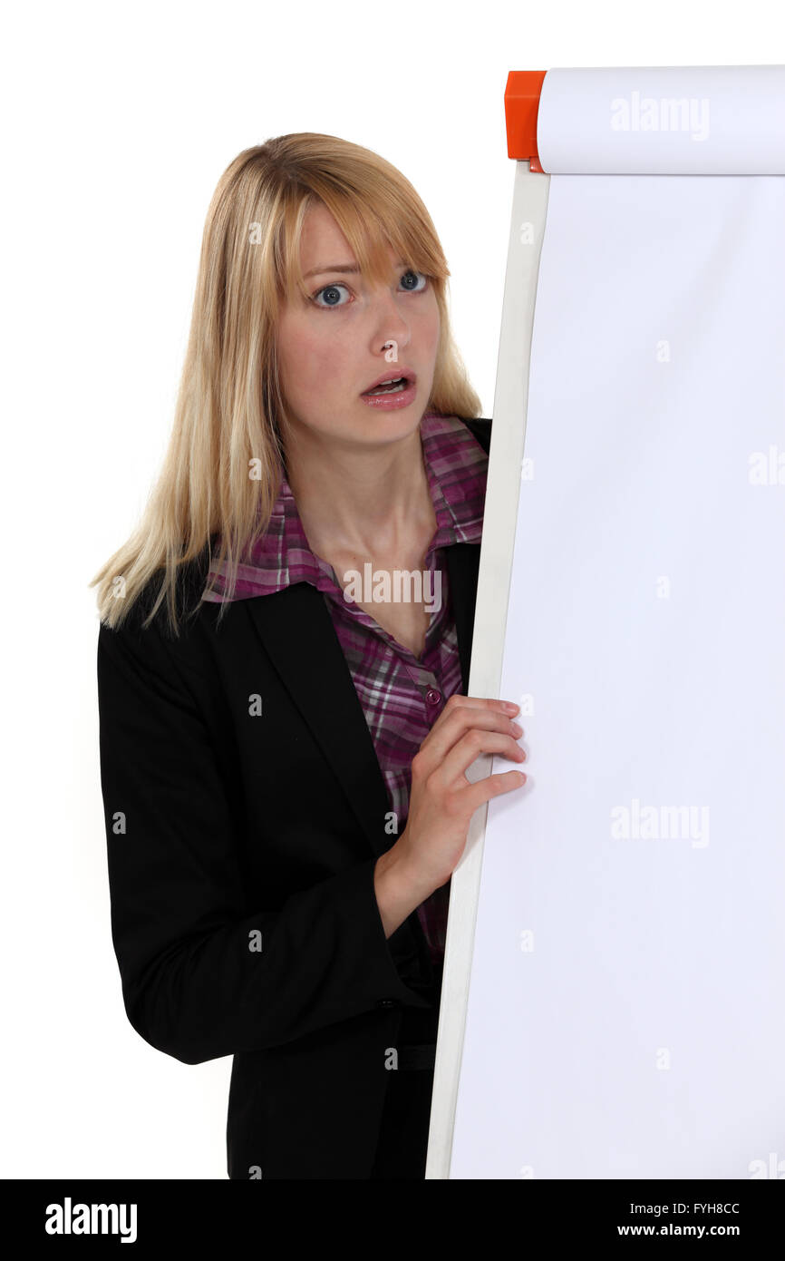 Shocked blond woman stood by blank flip chart Stock Photo