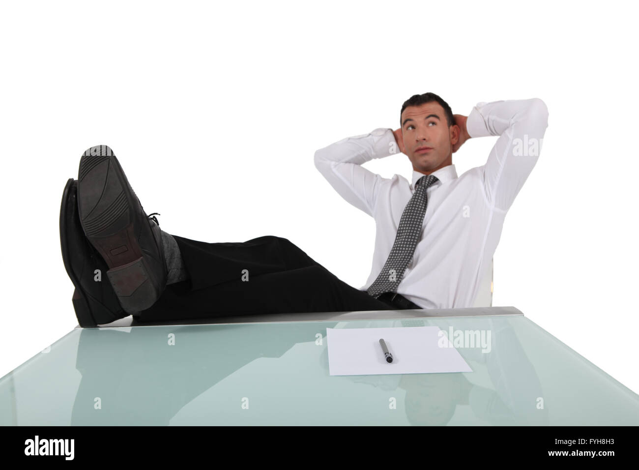 young businessman having a break with legs on table and arms behind