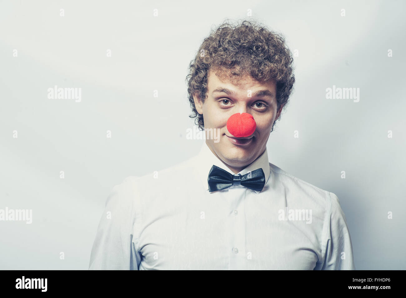 Young studen or Businessman with a red clown nose. Studio shot. Head and shoulders. Stock Photo