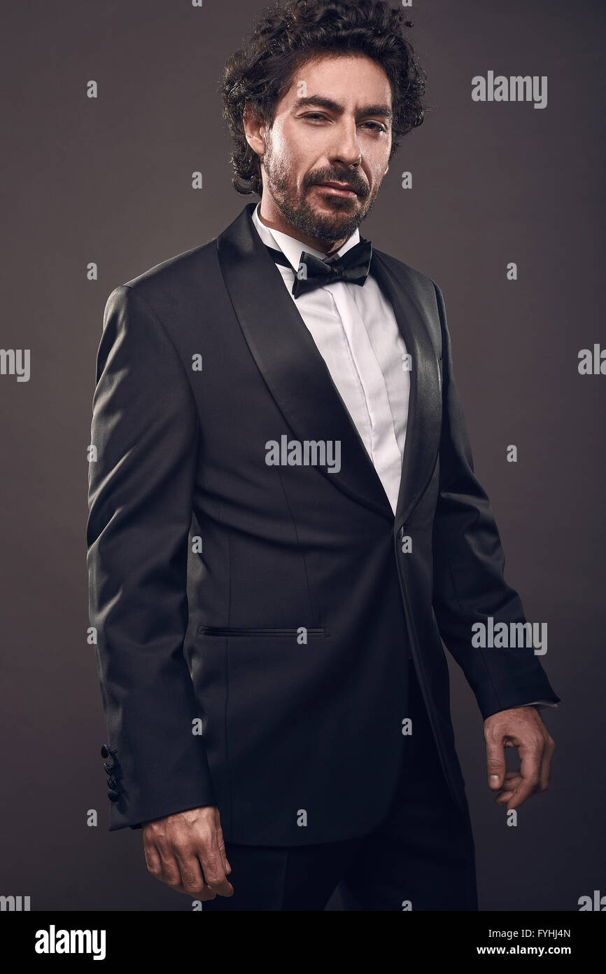 portrait of elegant brutal fashion man in suit looking at the camera.on black background Stock Photo
