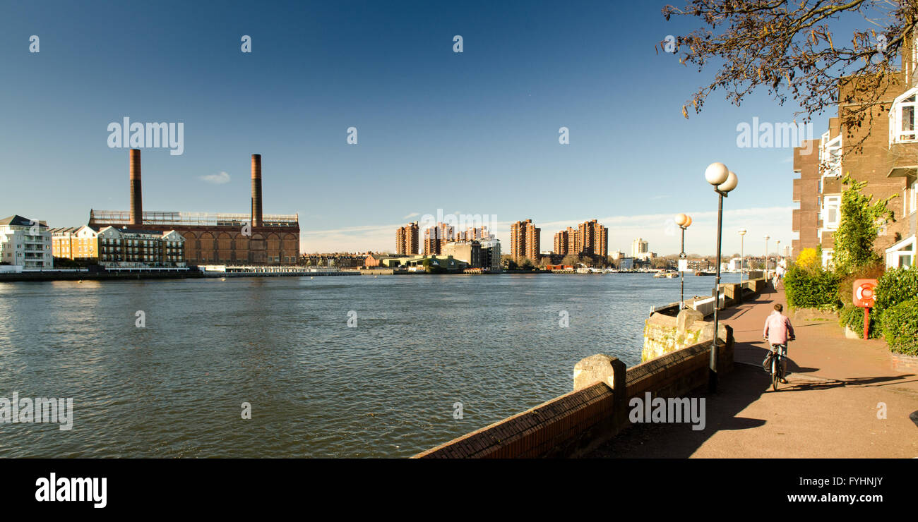 A cyclist on the Thames Path at Battersea, with Lots Road Power Station across the river. Stock Photo