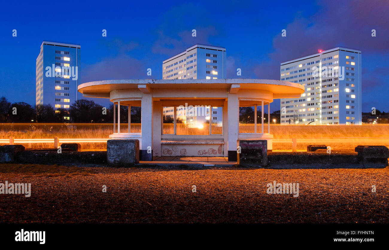 A modernist 1930s beach shelter at Weston Shore on Southampton Water, with a row of three council estate tower blocks behind. Stock Photo