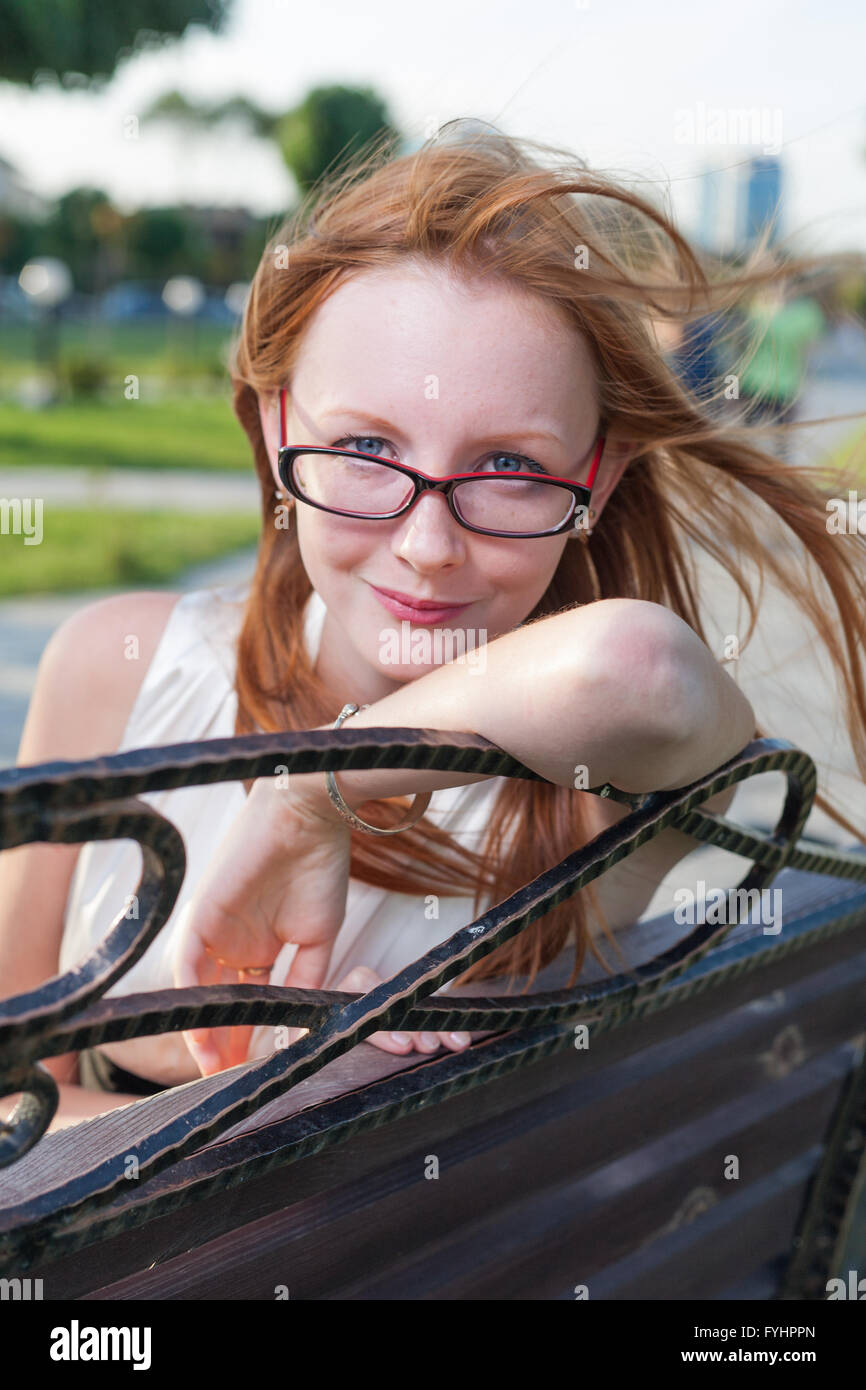 Beautiful young female sitting on the bench in summer park Stock Photo ...