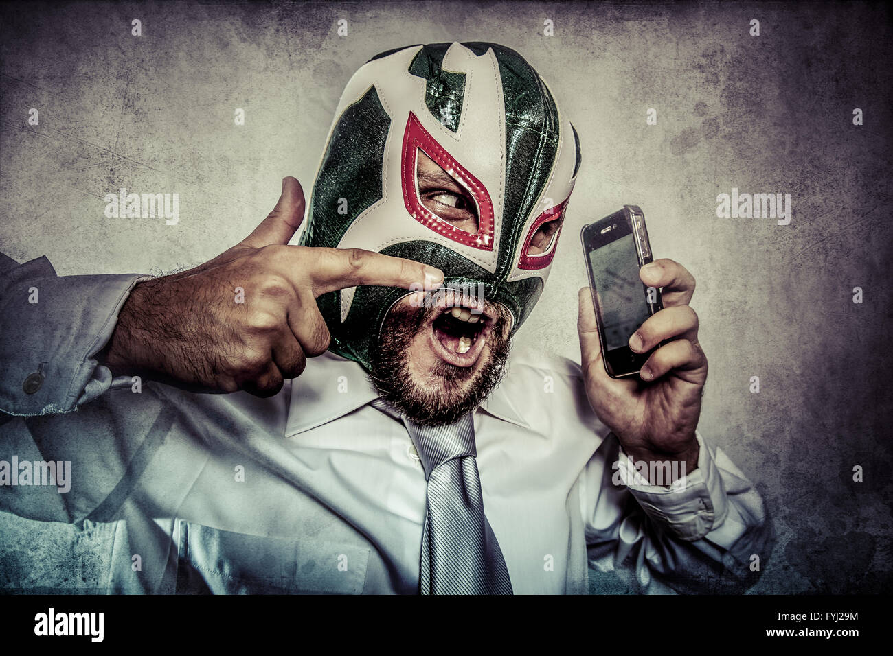 man arguing by phone, aggressive executive suit and tie, Mexican wrestler mask Stock Photo