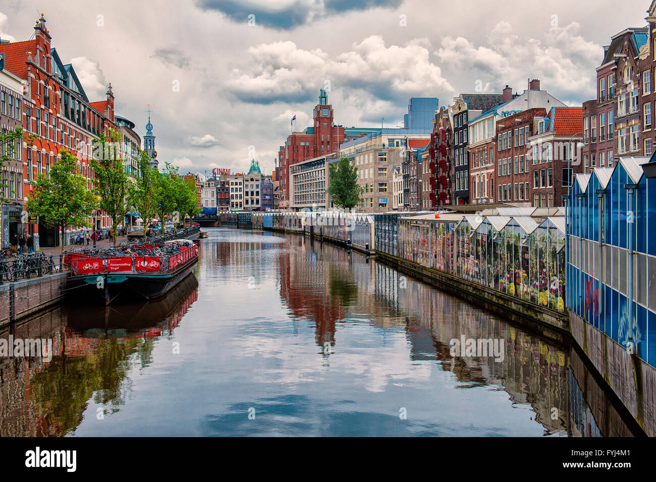 Amsterdam, Netherlands. The beautiful Singel canal with its reflections of sky and clouds. To the right the famous Flower Market Stock Photo