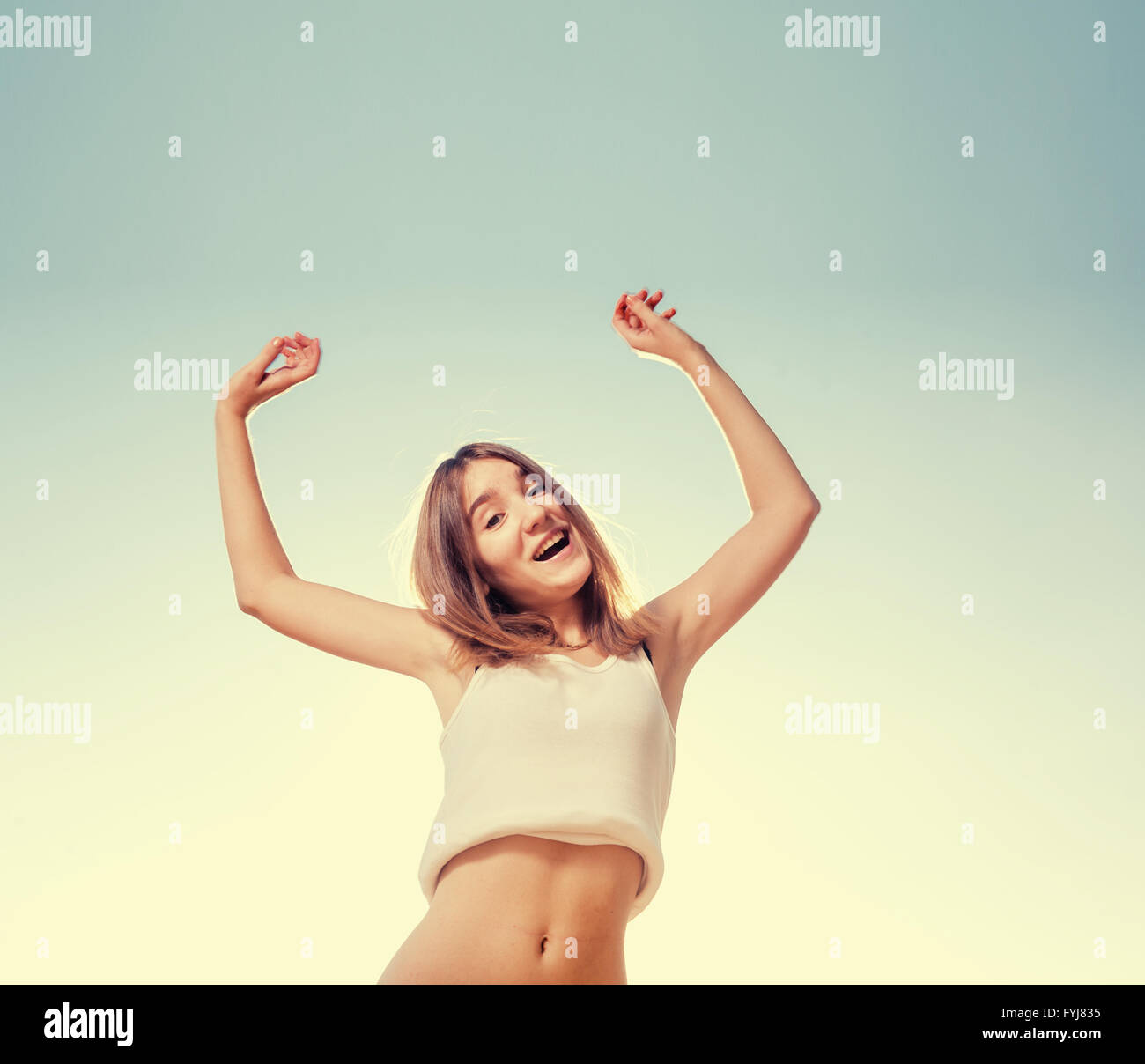 Blonde teenager girl jumping happy with the blue sky in the back Stock ...