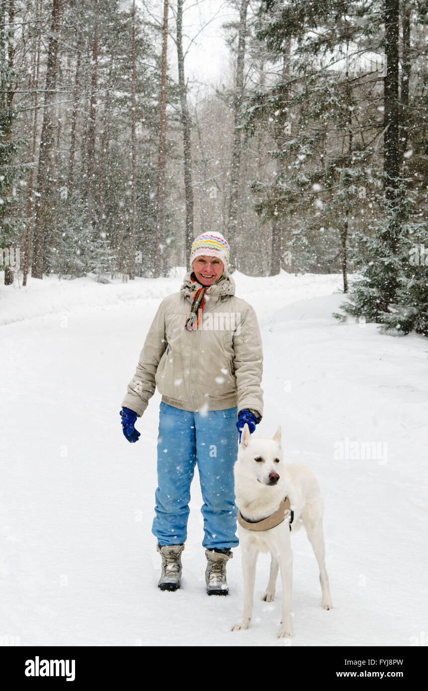 Woman with a dog on a walk in the woods during a snowfall Stock Photo ...