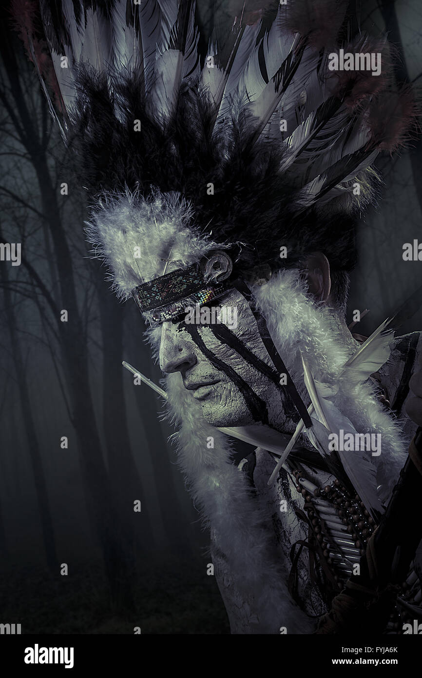 American Indian chief of the tribe. man with feather headdress and tomahawk Stock Photo
