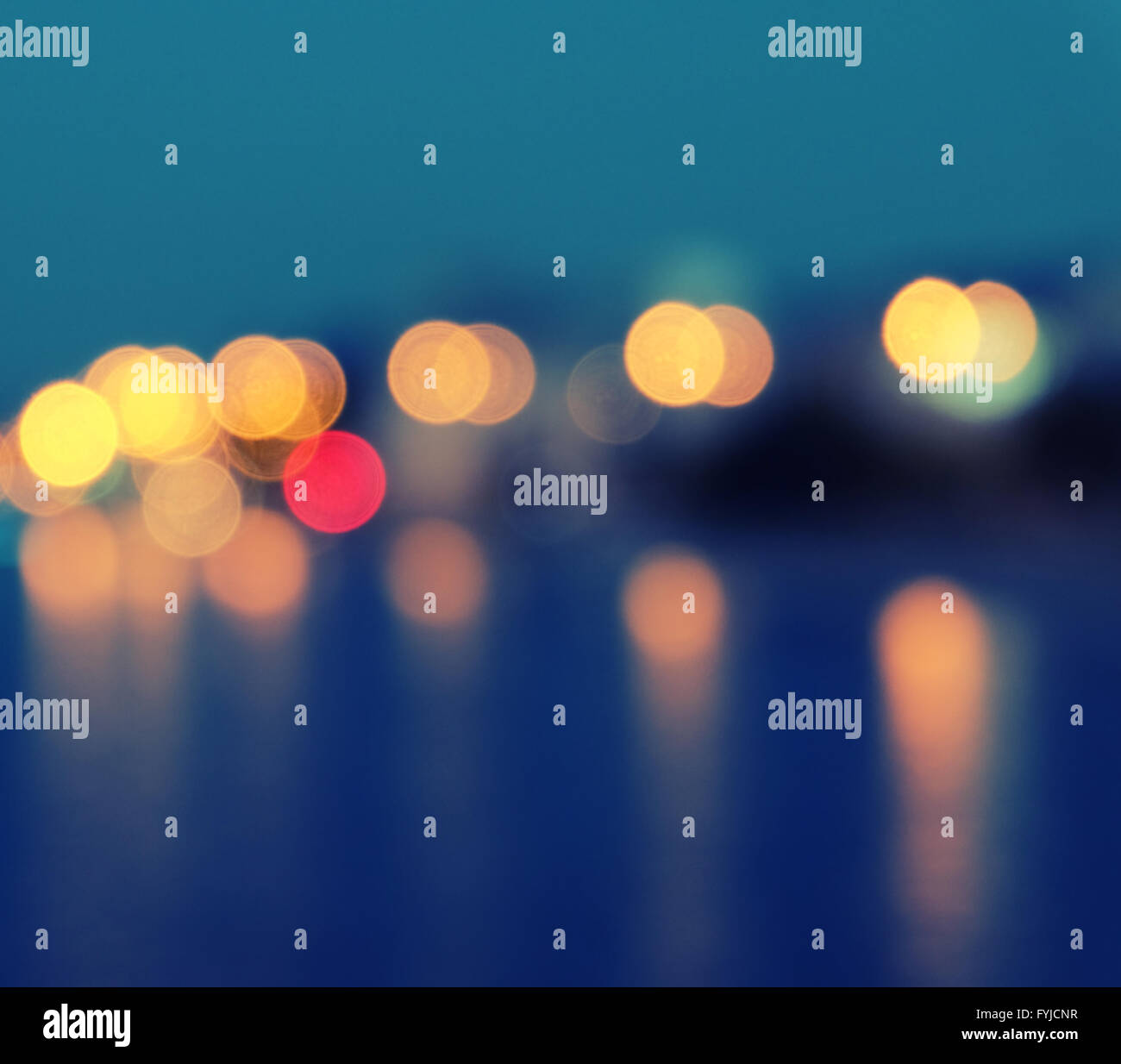 Square image of a blurred city lights with bokeh effect reflected on water. Stock Photo