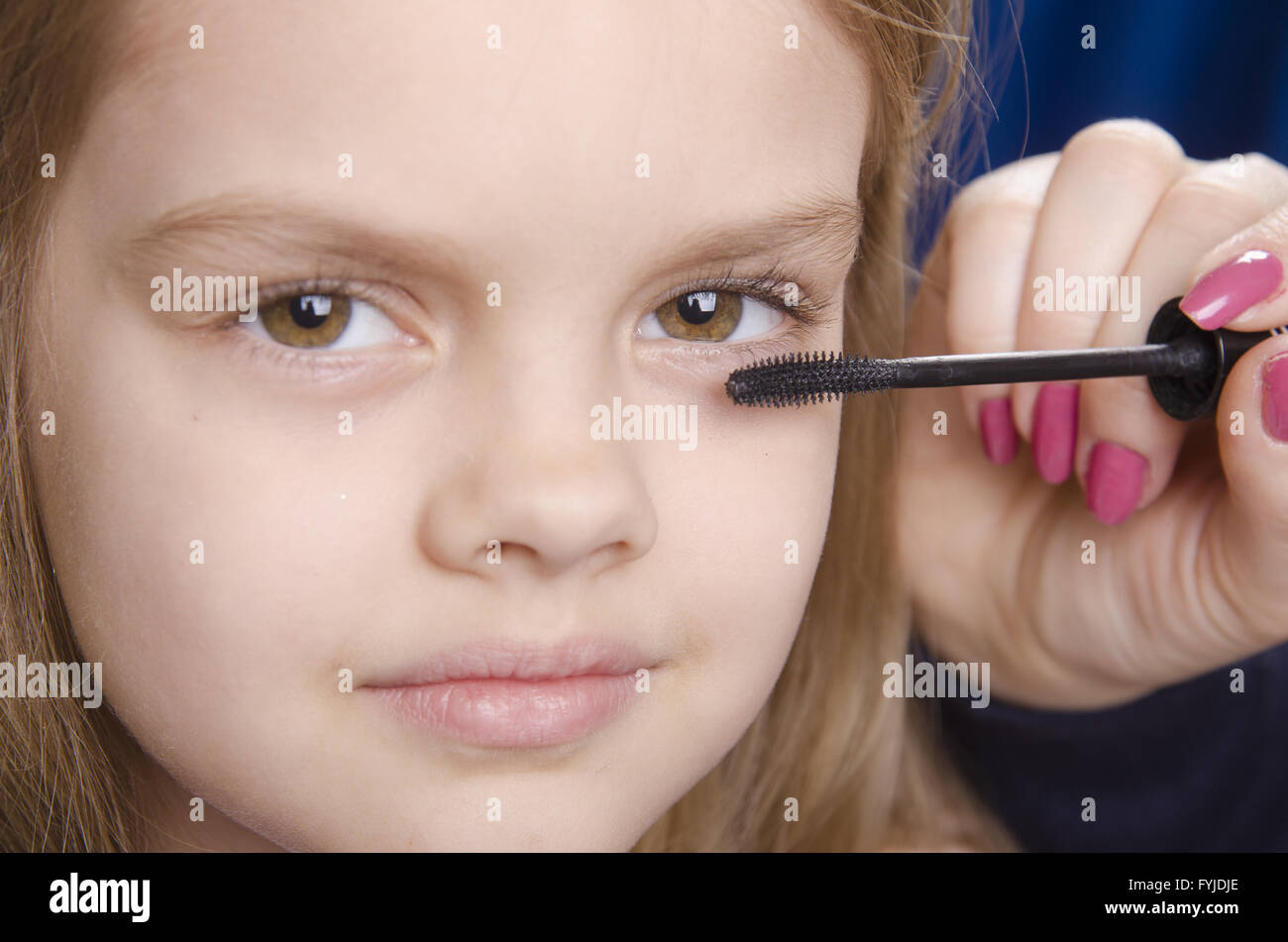 Makeup artist paints eyelashes on girl's face Stock Photo