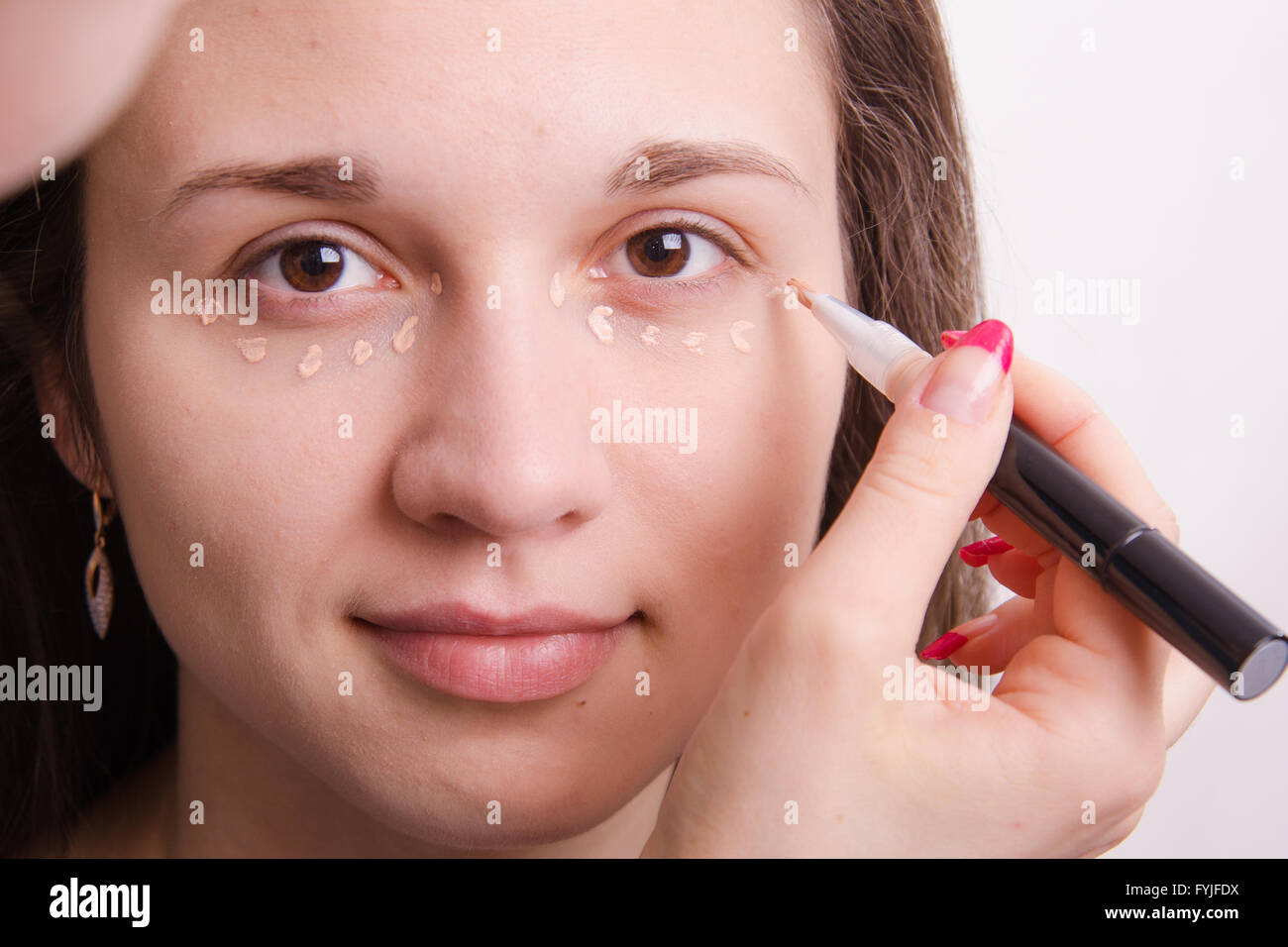Makeup artist applies foundation on eyelids of young girl Stock Photo