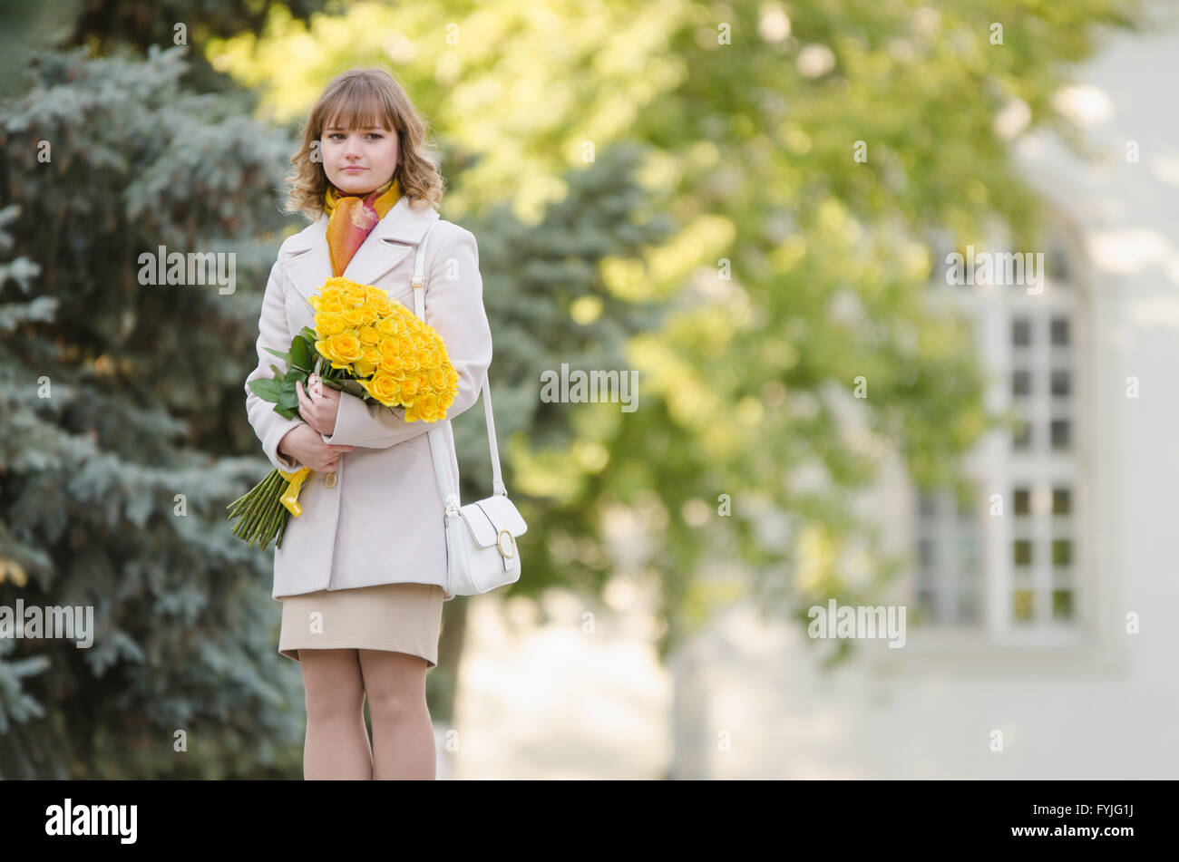 Cute little girl with a bouquet of yellow roses walks in the park Stock Photo