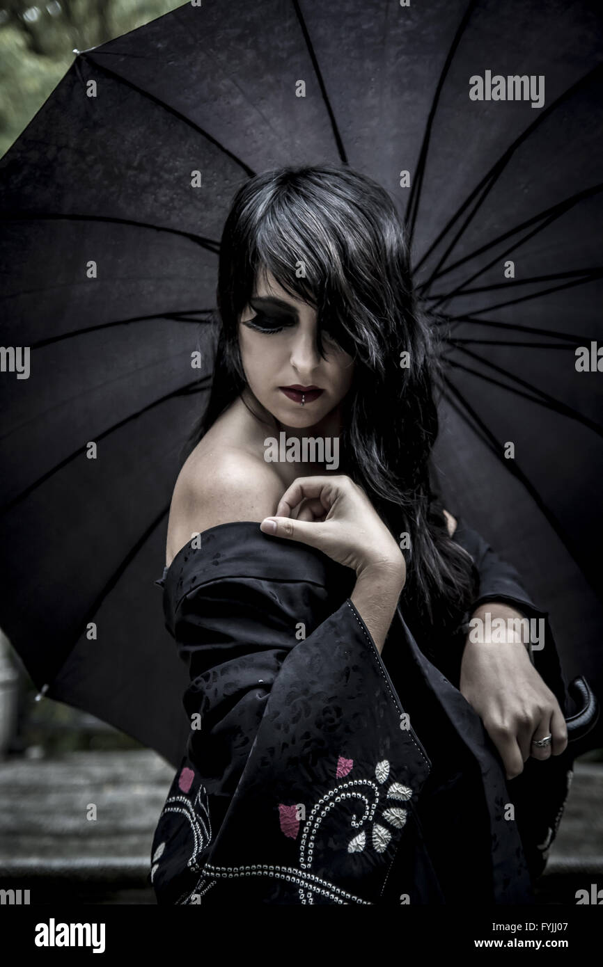 Japanese look, pretty young woman with black umbrella, under autumn rain in a palace park Stock