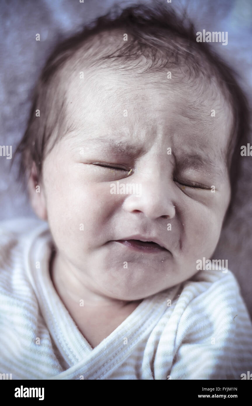 new born baby curled up sleeping on a blanket, multiple expressions