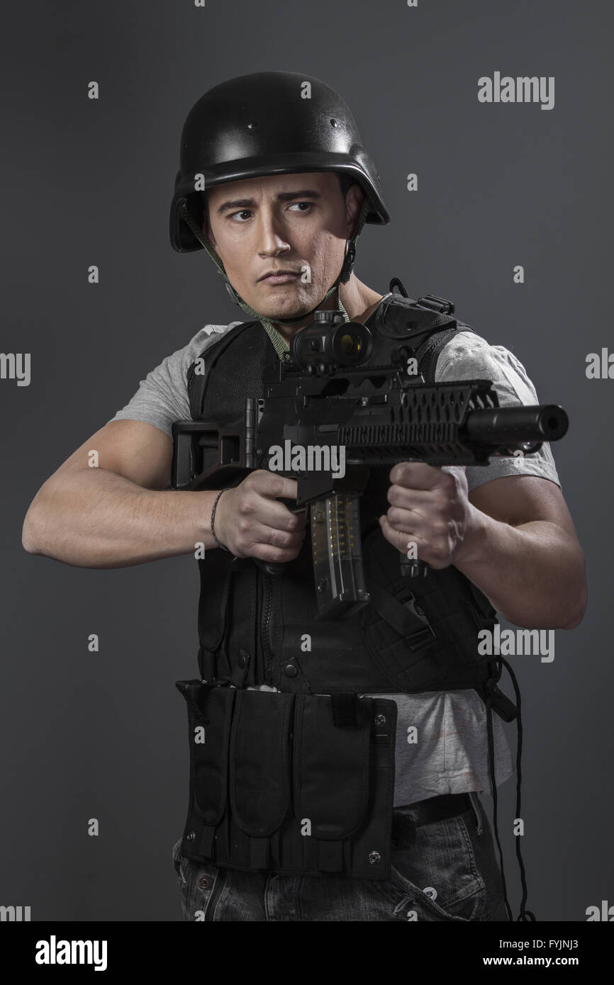 Soldier, paintball sport player wearing protective helmet aiming pistol