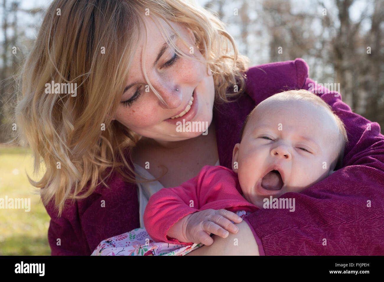 Baby is yawning in mothers arms Stock Photo