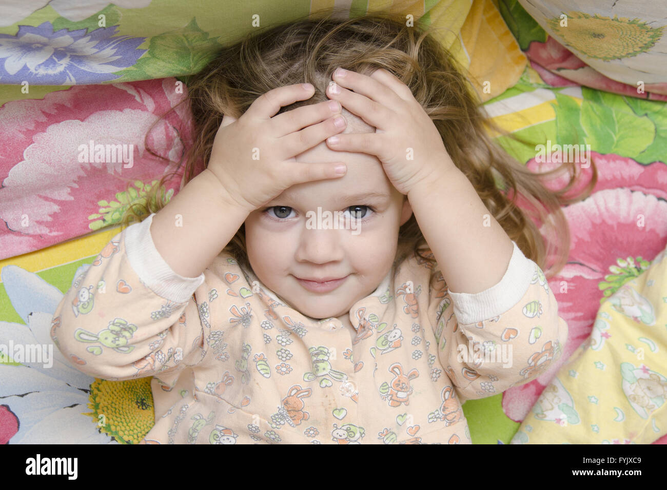 Twoyearold girl lying on bed and head in his hands Stock Photo Alamy
