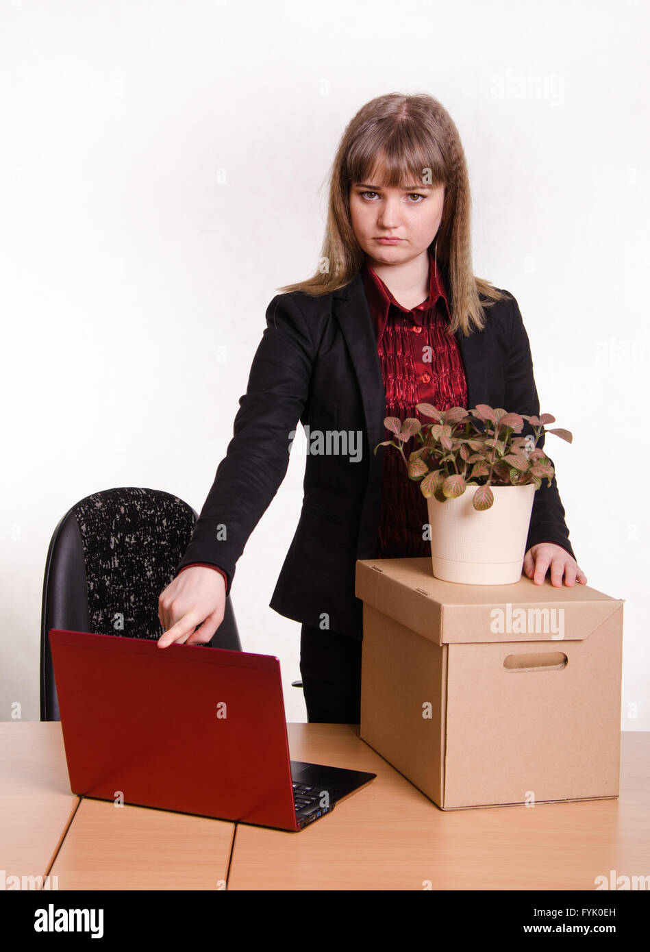 Dismissed girl in office collects things and closes laptop Stock Photo