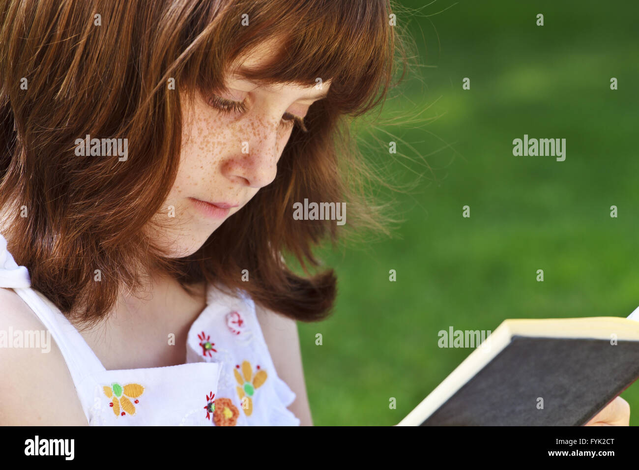 Young beautiful girl reading a book outdoor Stock Photo - Alamy