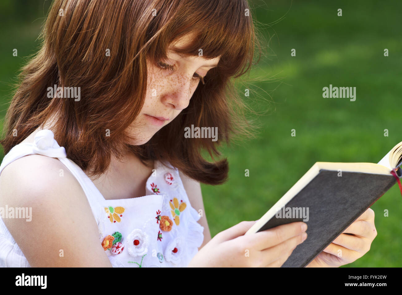 Young beautiful girl reading a book outdoor Stock Photo - Alamy