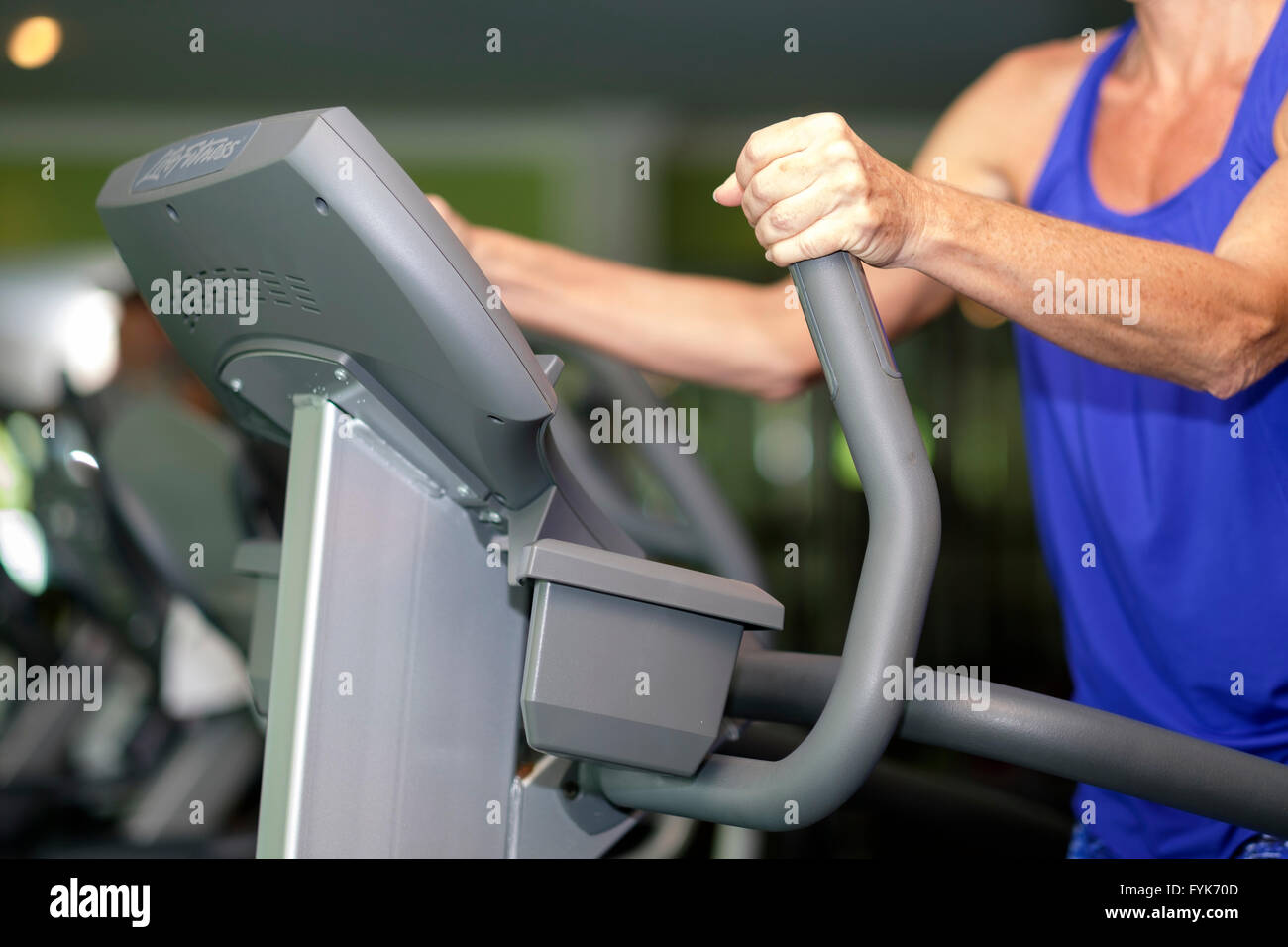 Mature woman exercising on elliptical stepper at a gym Stock Photo
