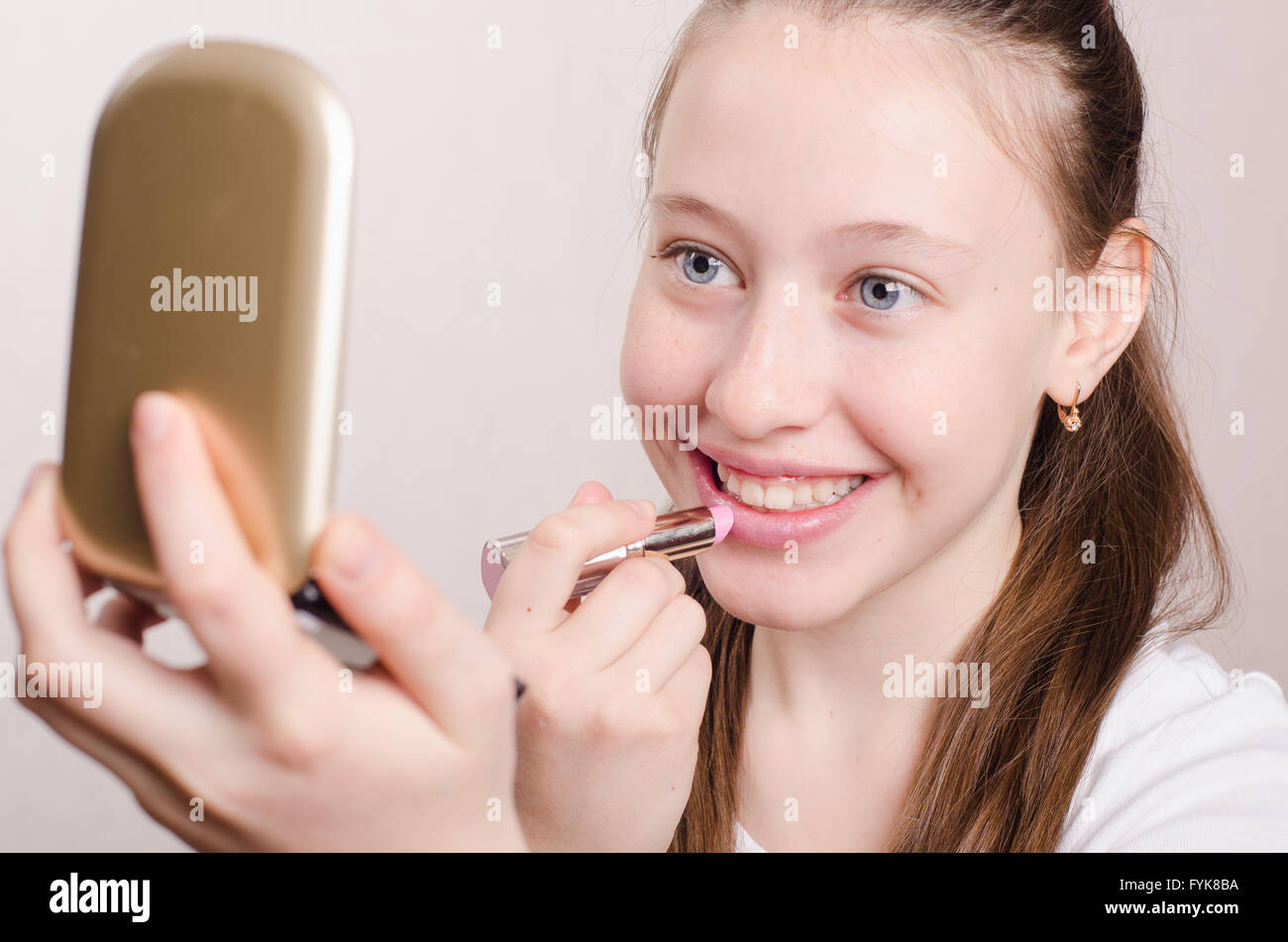 Twelve year old girl paints lips with lipstick Stock Photo Alamy