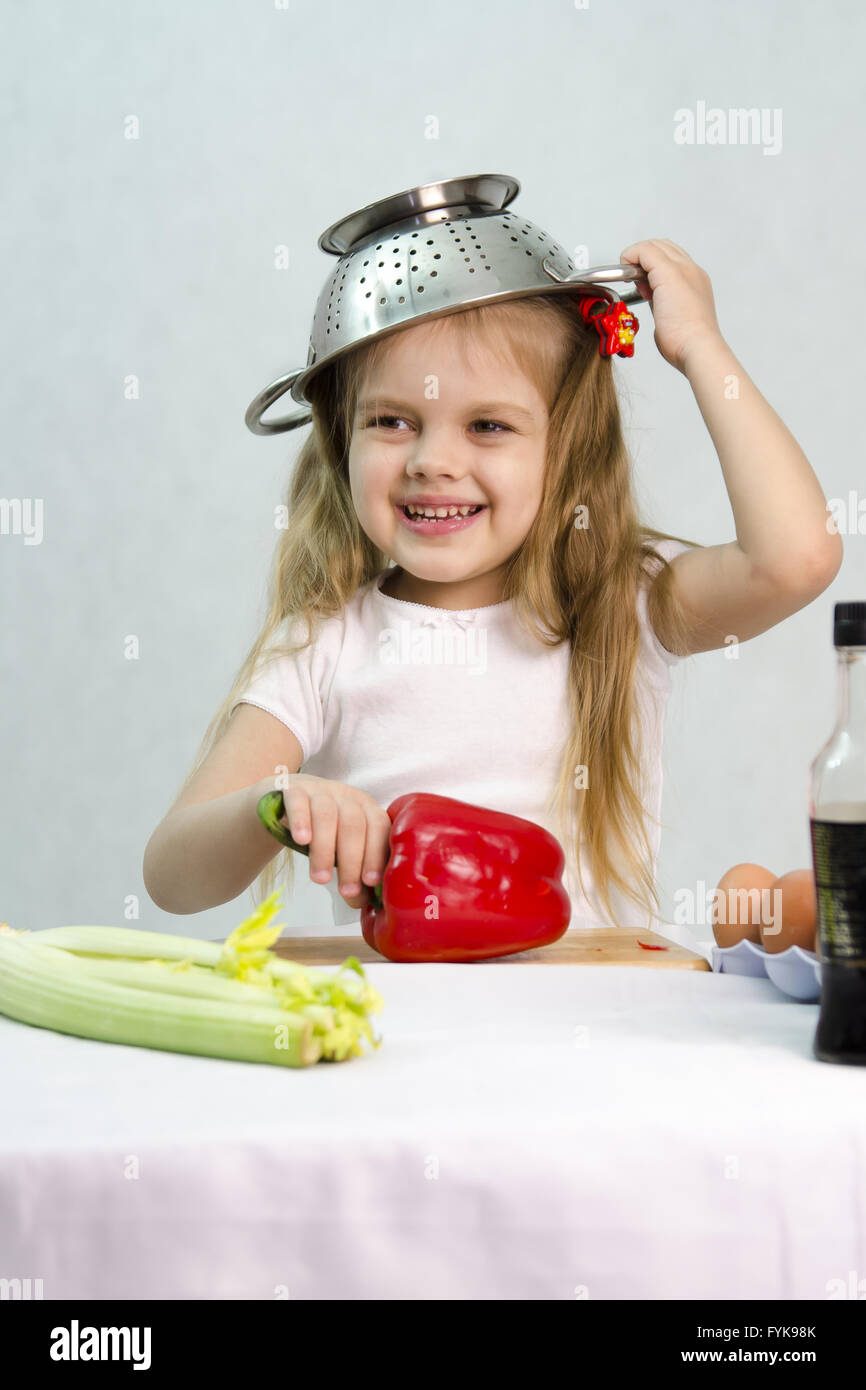 Girl playing in cook put a colander on his head Stock Photo Alamy