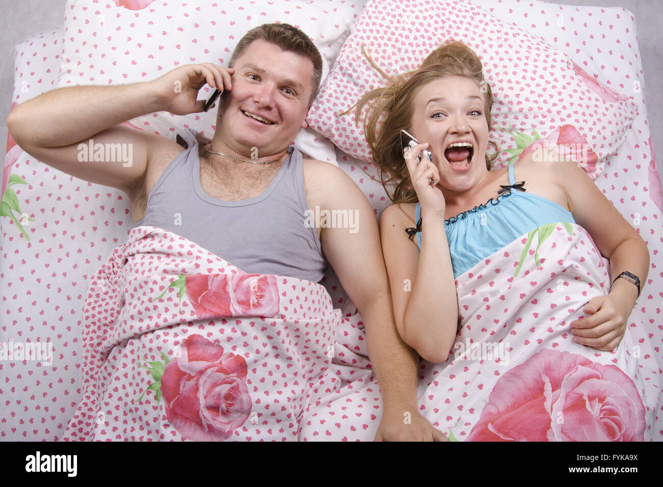 Young couple talking on the phone lying in bed Stock Photo