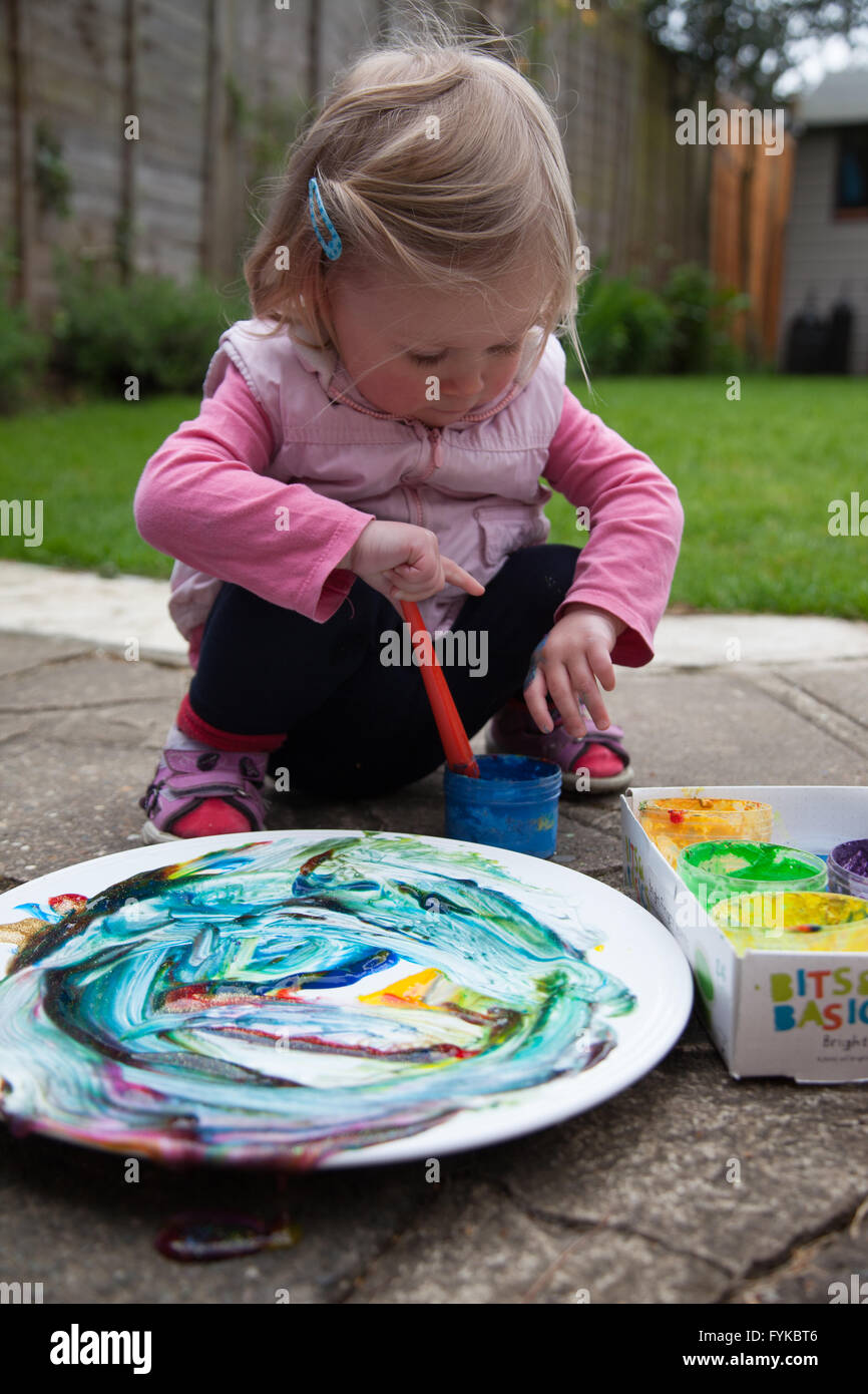 Girl painting on a plate in the back garden Stock Photo