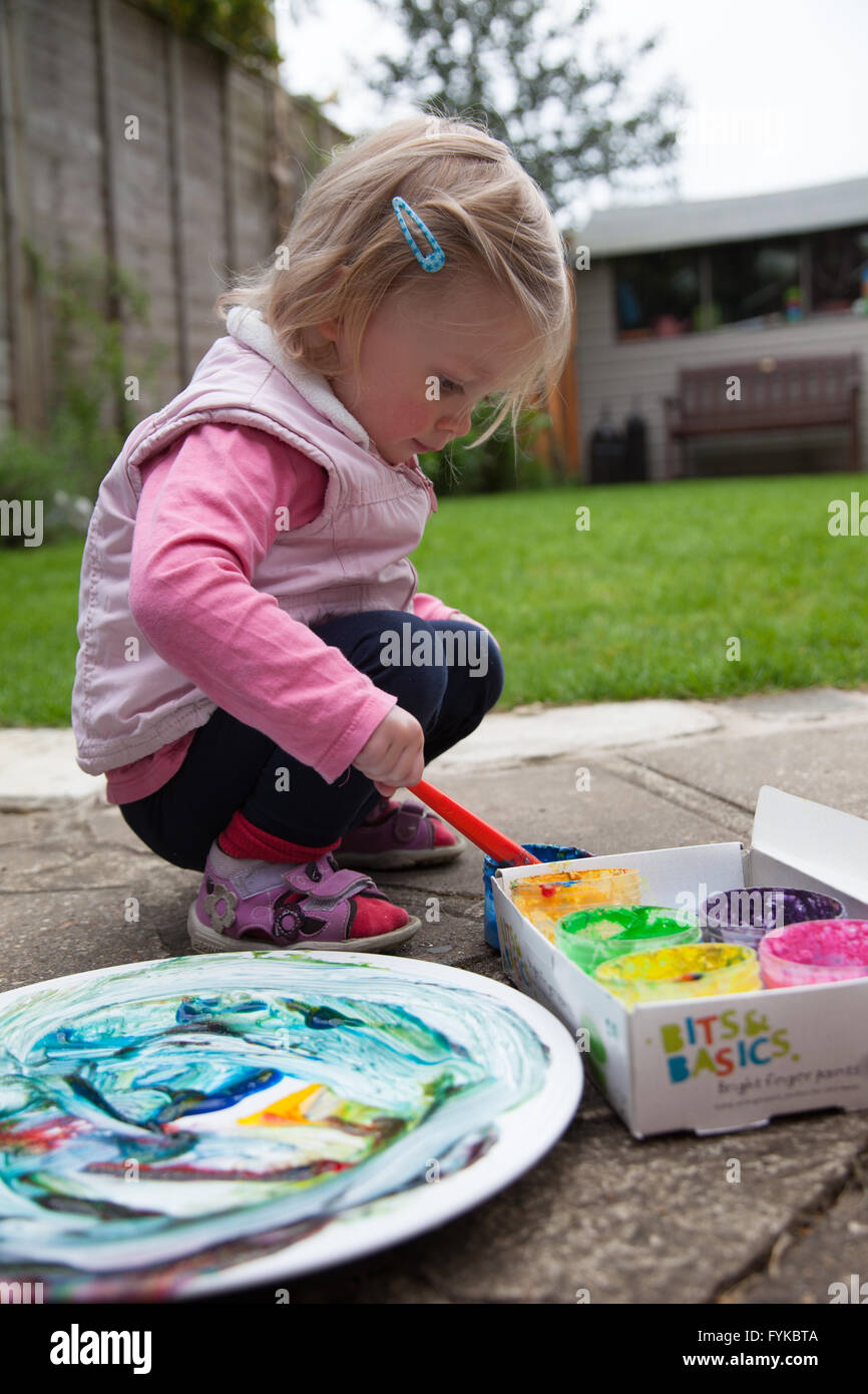 Girl painting on a plate in the back garden Stock Photo