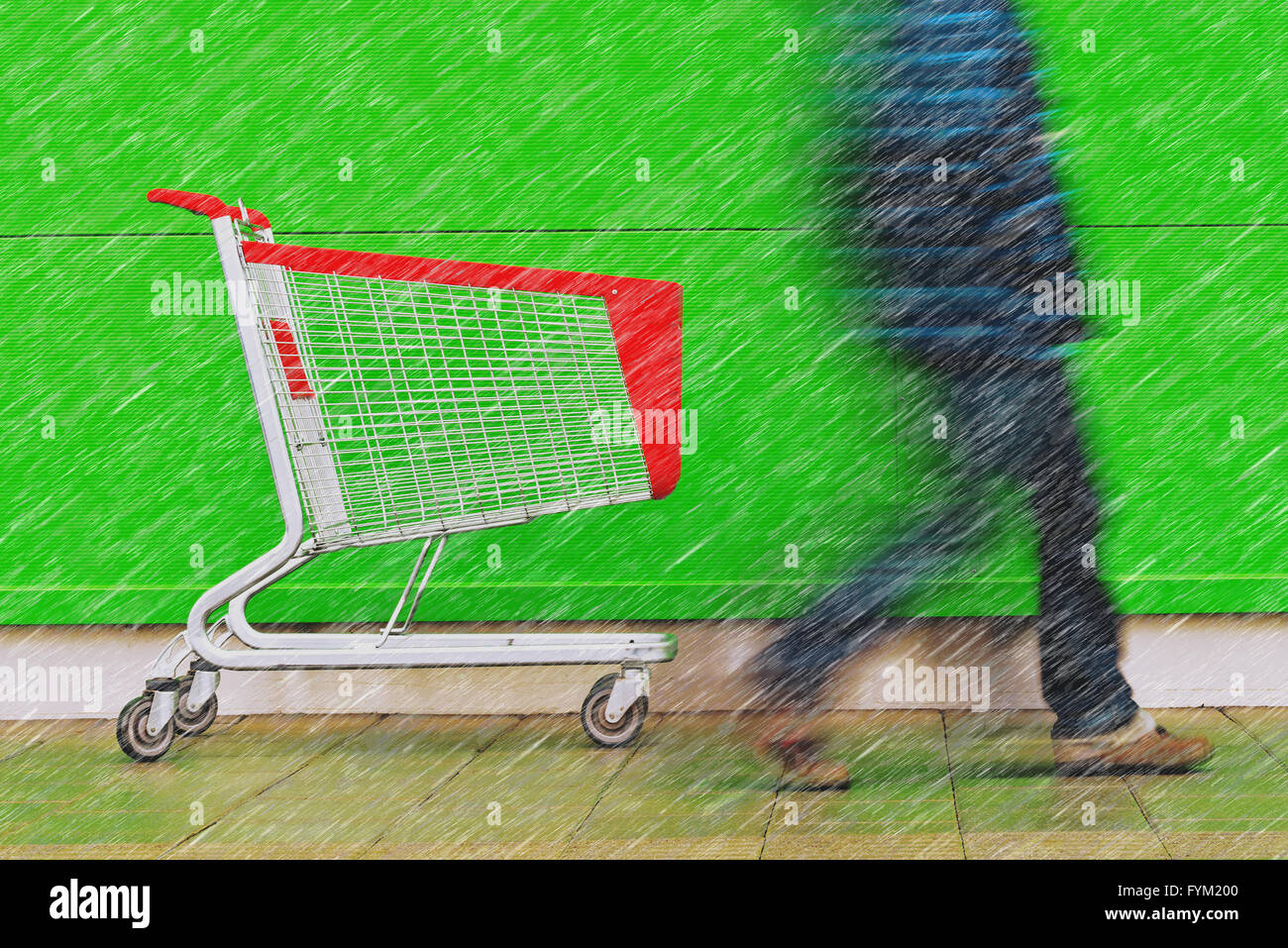 Shopping on a rainy day, motion blur man walking by empty cart trolley in front of a supermarket. Stock Photo