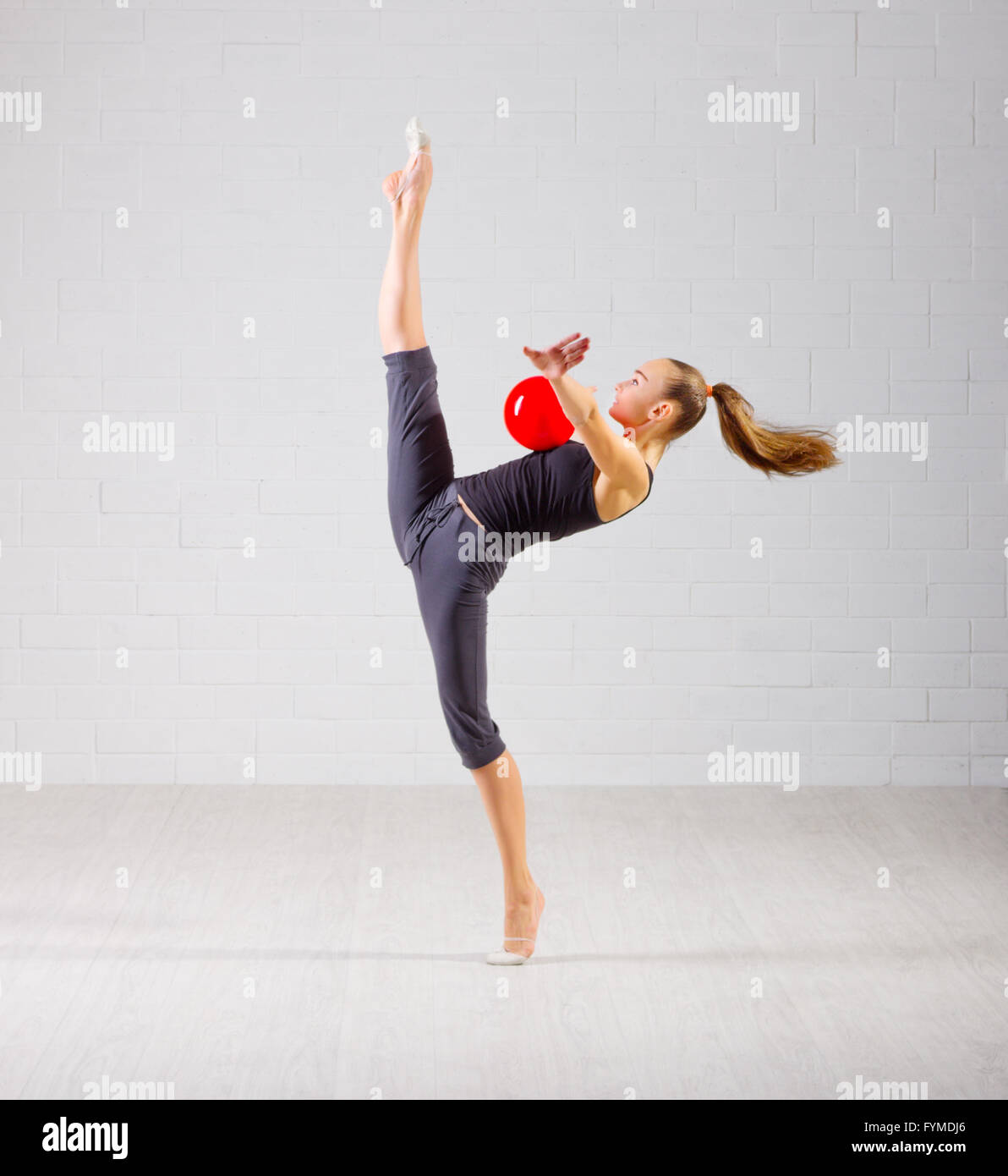 Young girl engaged art gymnastic on grey wall background Stock Photo