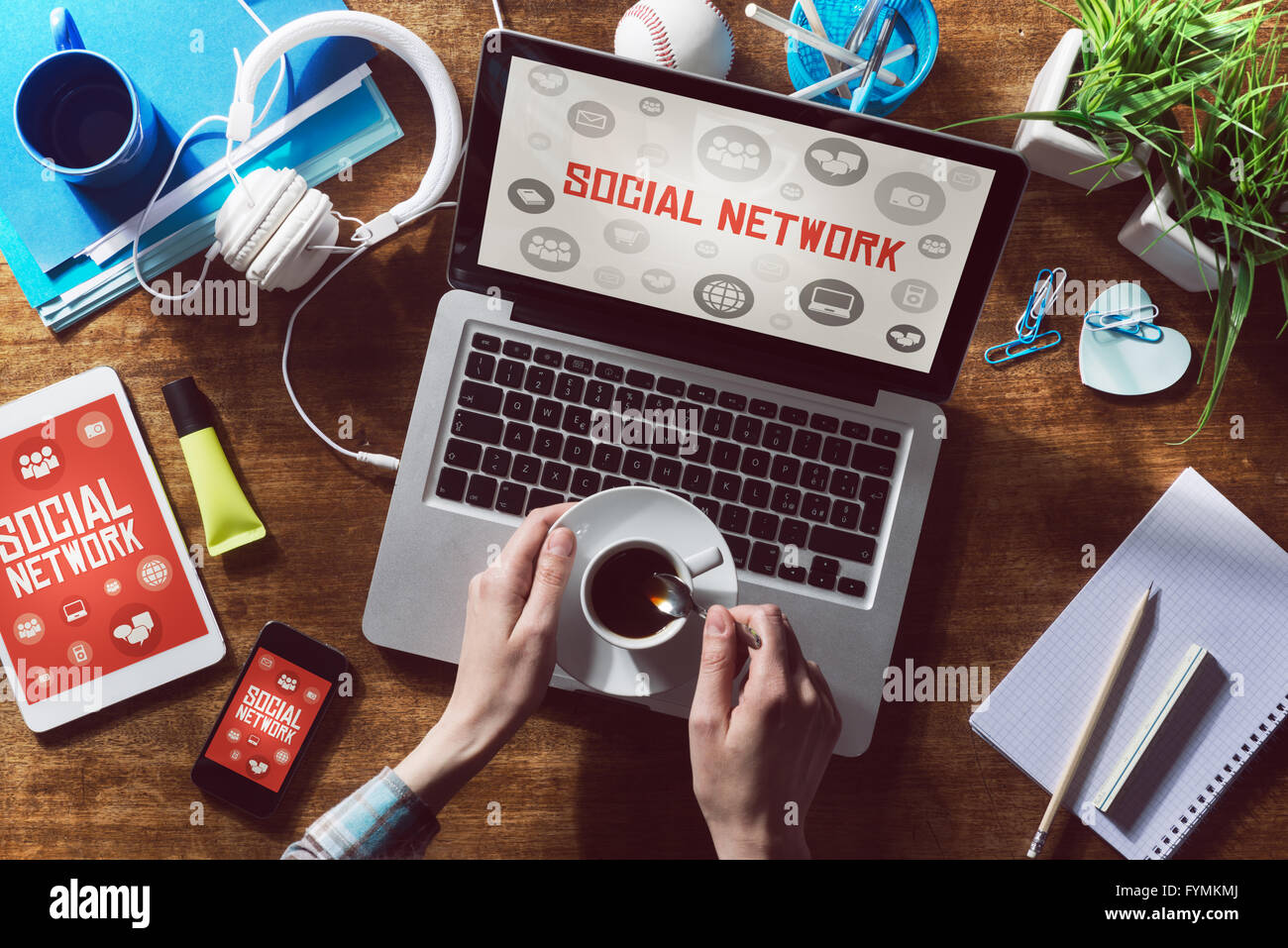 Social network website mock up on computer screen, tablet and smartphone with hands holding a cup of coffee Stock Photo