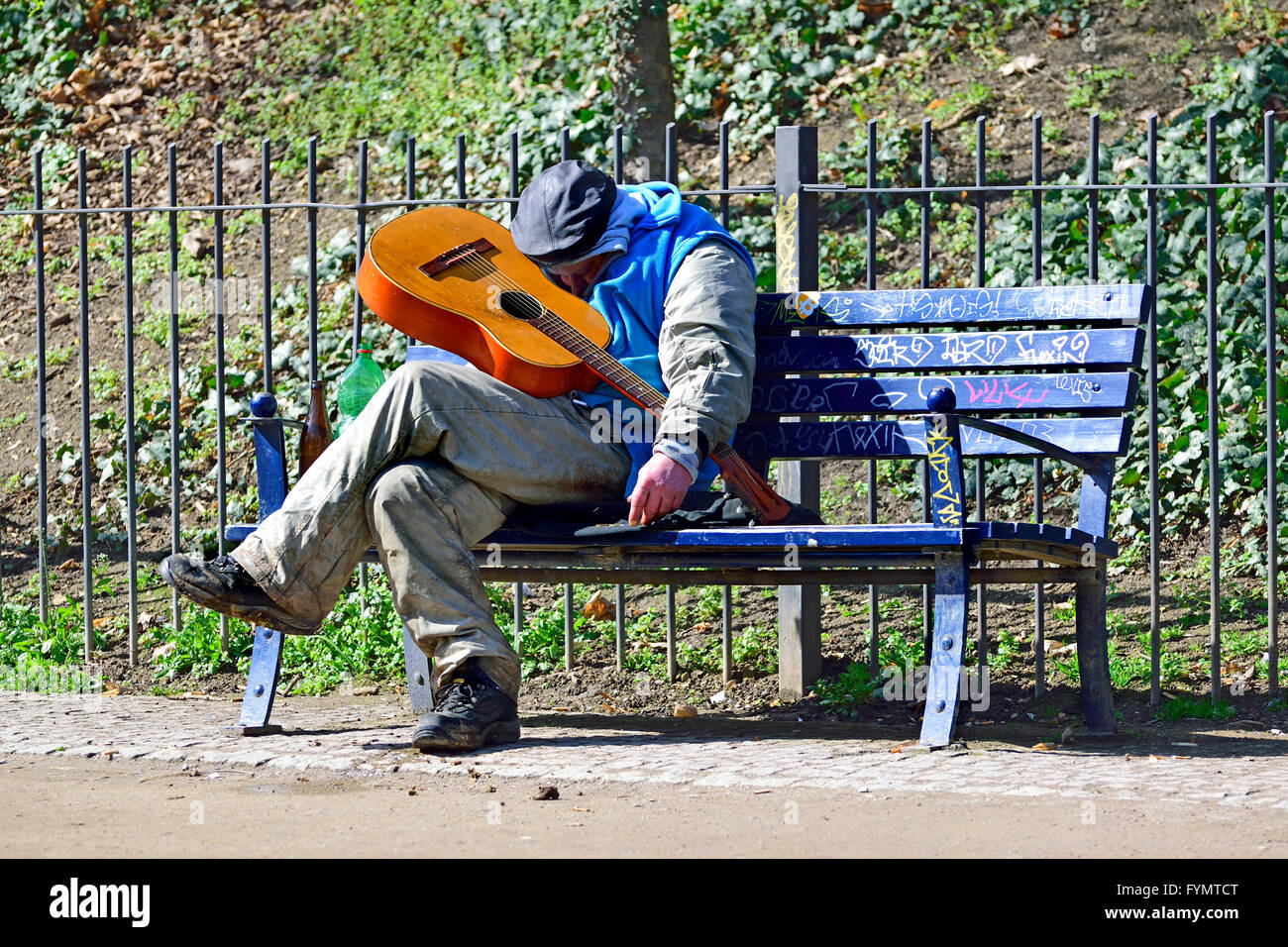 Prague, Czech Republic. Man asleep on a bench with a guitar Stock Photo