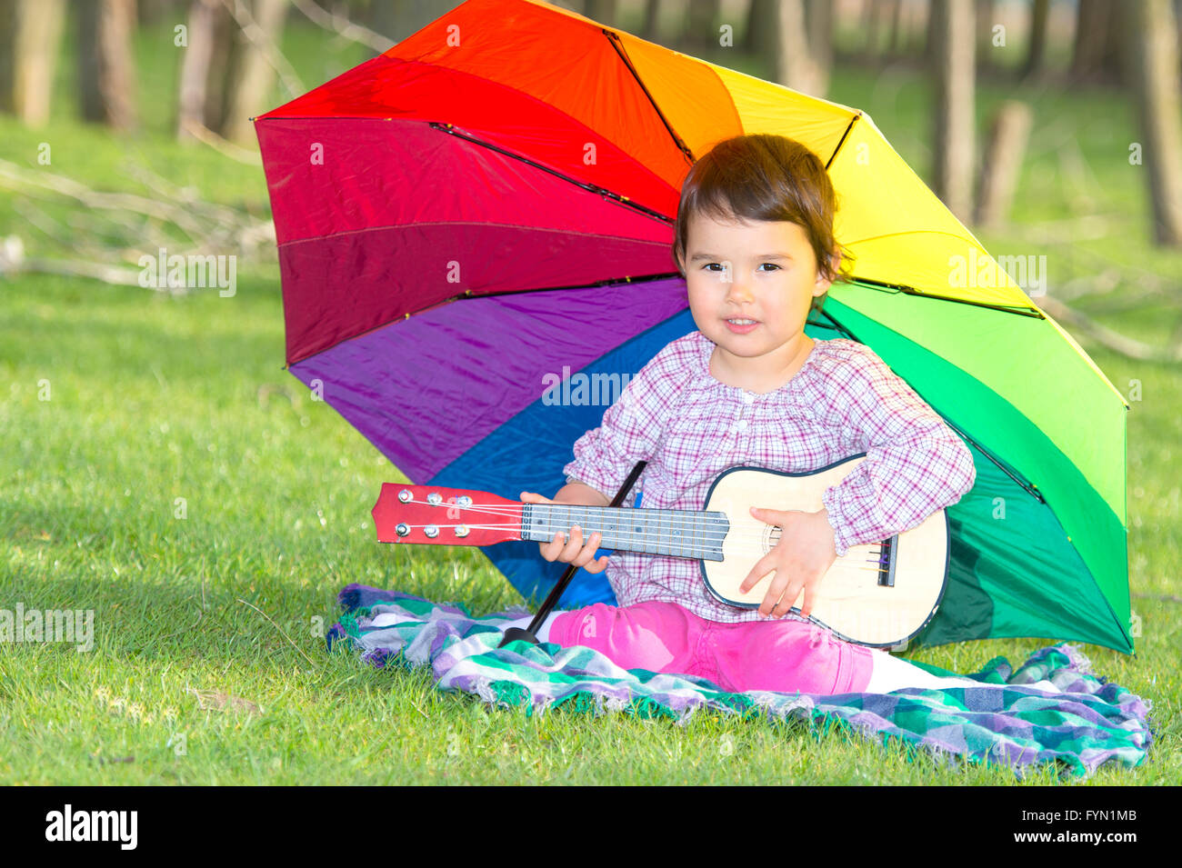 little happy girl with a rainbow umbrella and guitar in park Stock ...