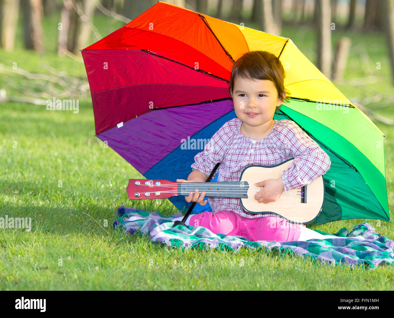 little happy girl with a rainbow umbrella and guitar in park Stock ...