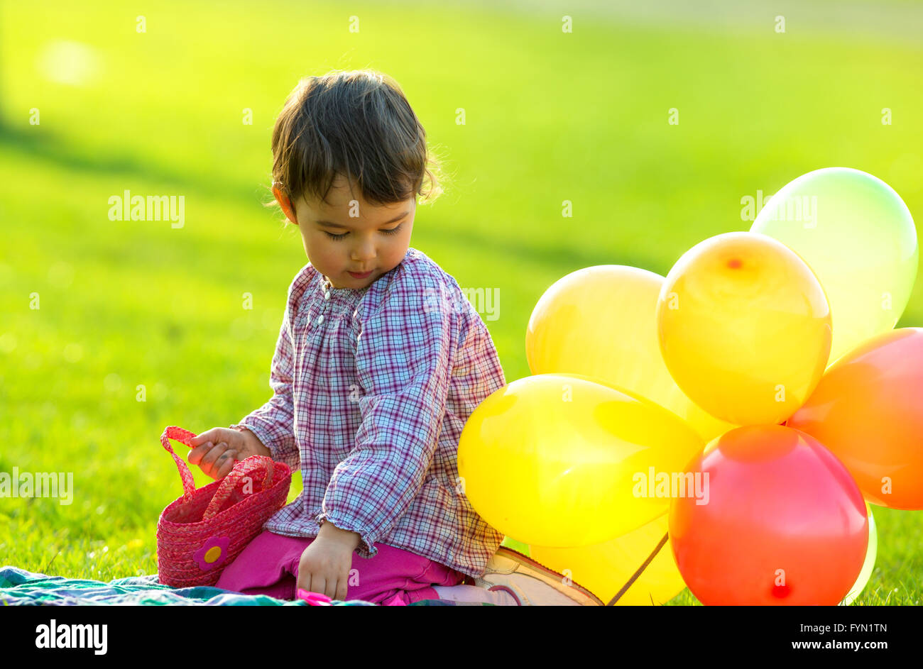 little girl sitting on the grass with balloons Stock Photo - Alamy
