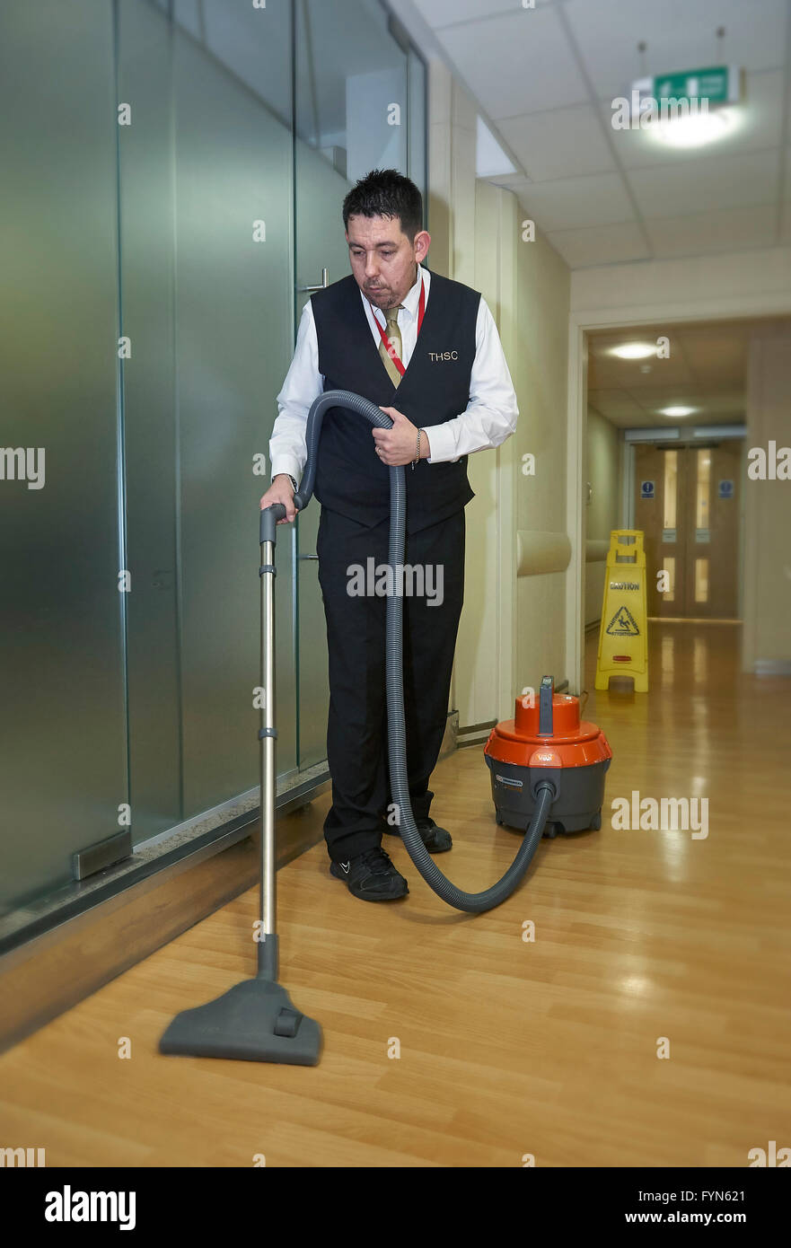 Porter vacuuming the hallway in a Hospital in the UK. Stock Photo