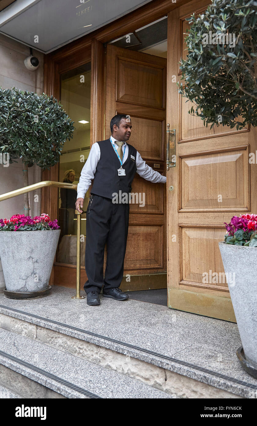 A Hotel Bellboy Or Porter Opening The Front Door Of A Hotel For A Guest In The Uk Stock Photo Alamy