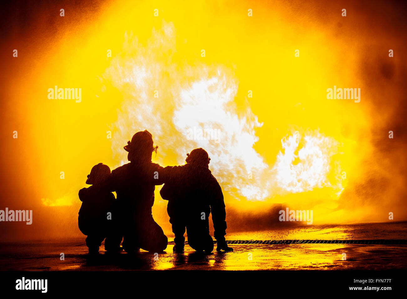 Firefighters in front of a burning tank Stock Photo