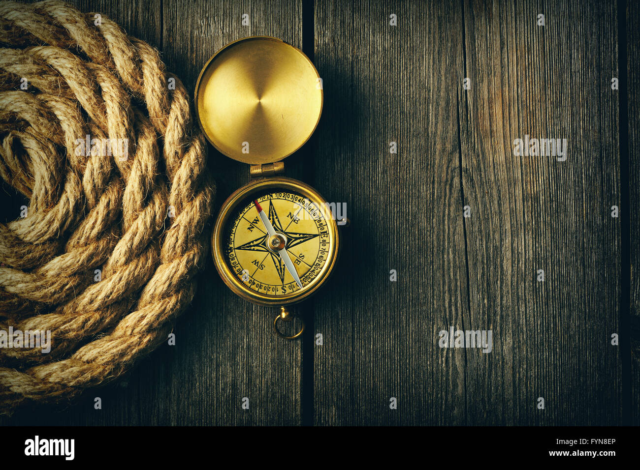 Antique compass and rope over wooden background Stock Photo