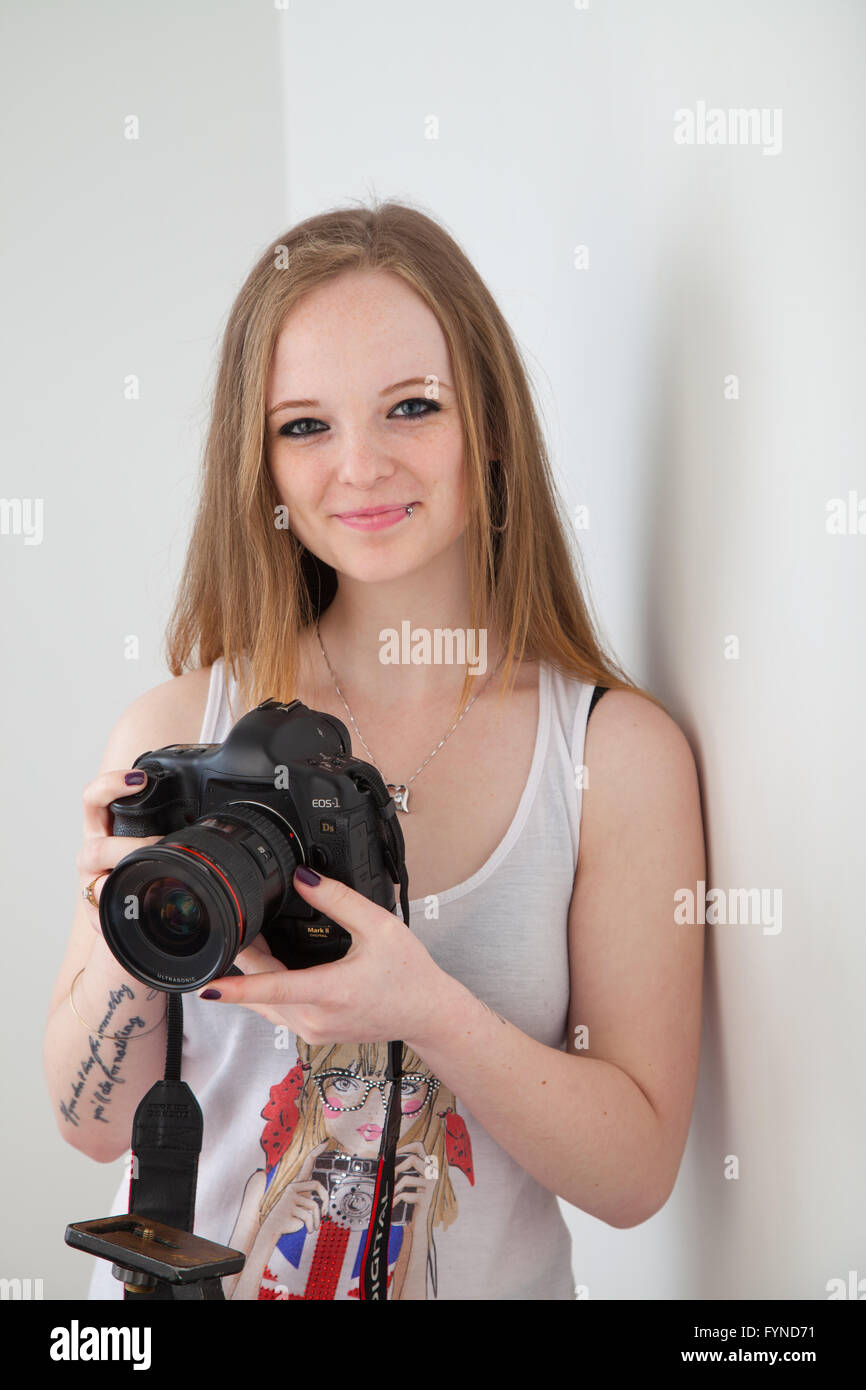 A redheaded woman holding a DSLR camera in her hands. Stock Photo
