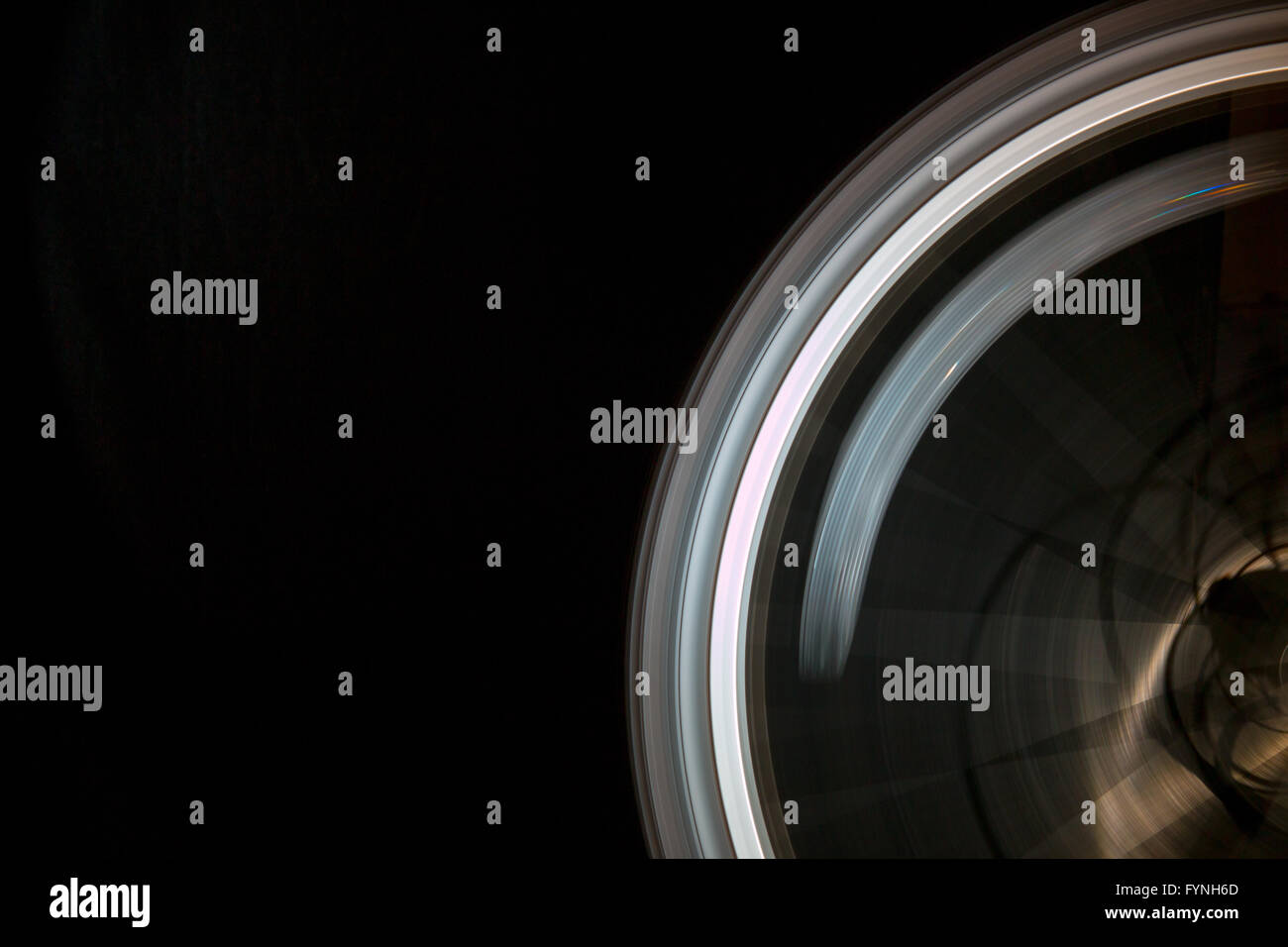 A spinning round bicycle wheel in motion while the safety reflector shows a small refraction from the light source.  the spokes are lit too. Stock Photo