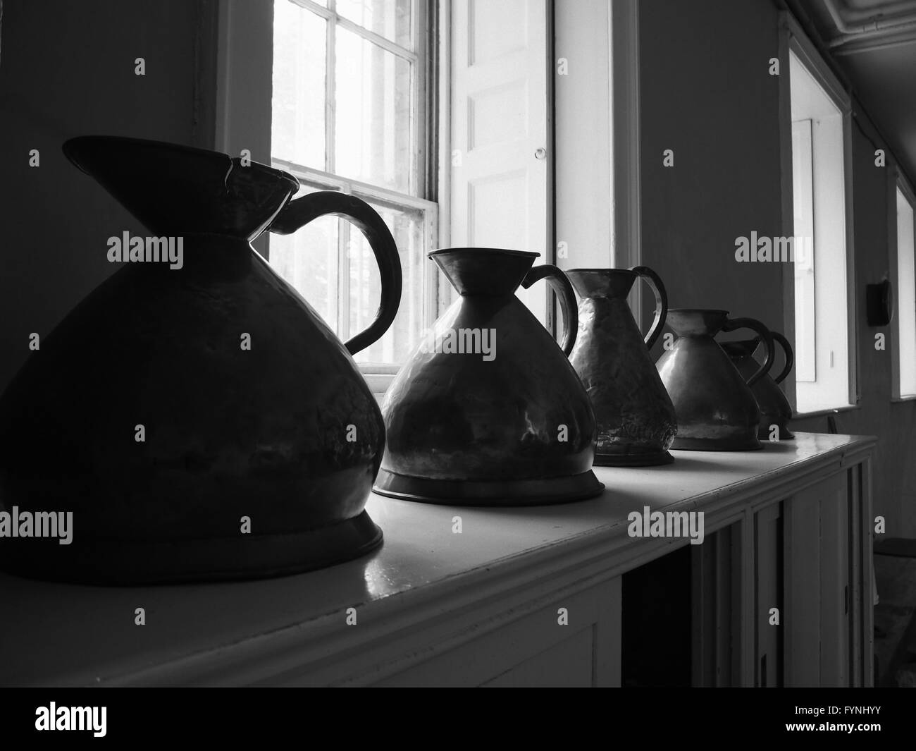 Mono image of vintage jugs by the window in an old kitchen in an English country house Stock Photo