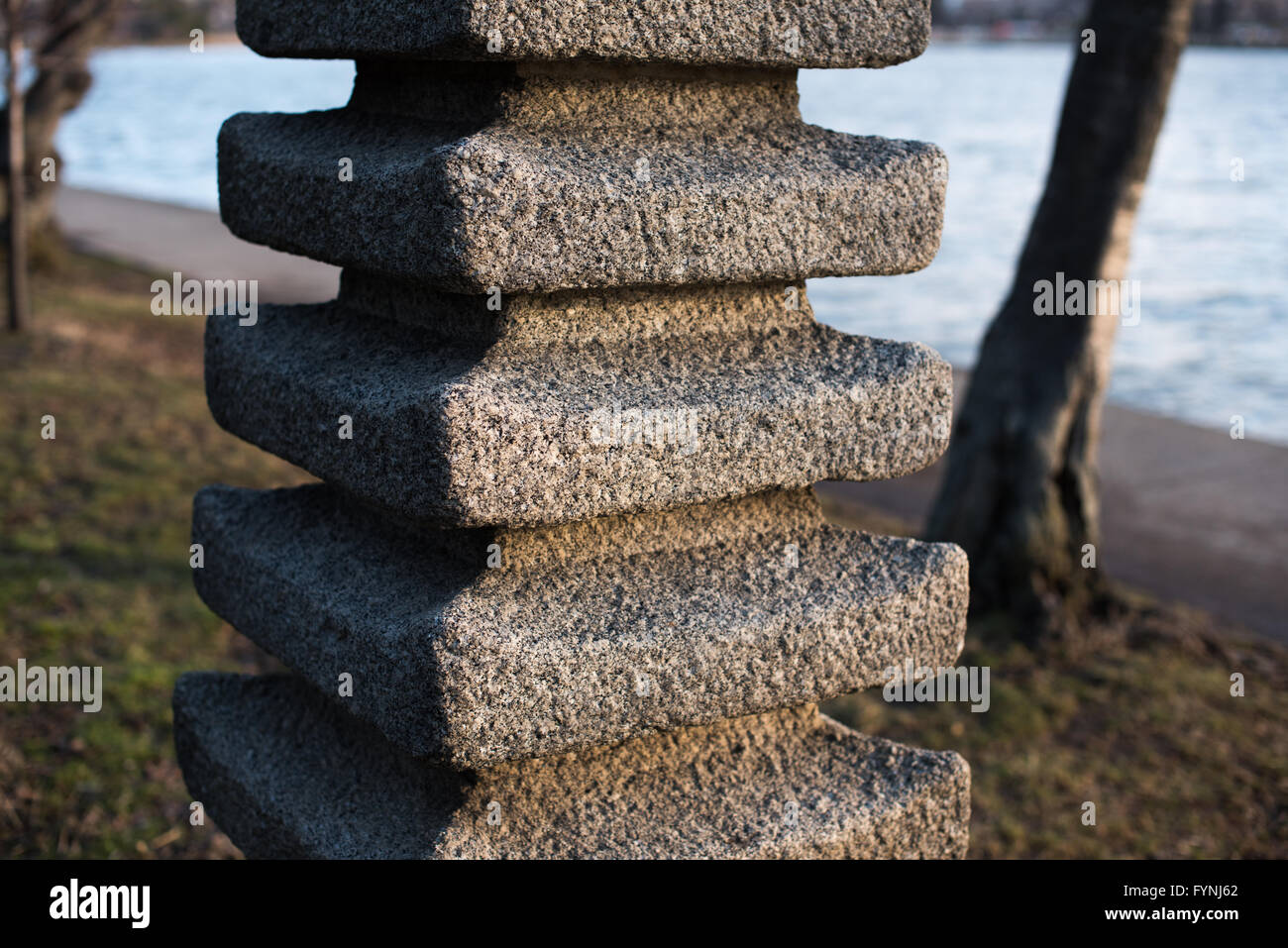 WASHINGTON, DC, United States — The Japanese Lantern, a 10-foot tall granite structure, stands among cherry trees at the Tidal Basin in Washington, DC. This traditional tōrō, gifted by Japan in 1954 to commemorate the 100th anniversary of U.S.-Japan relations, is surrounded by cherry blossoms. The lantern, lit annually during the National Cherry Blossom Festival, is located near the northern end of the Tidal Basin, with views of the Jefferson Memorial visible across the water. Stock Photo