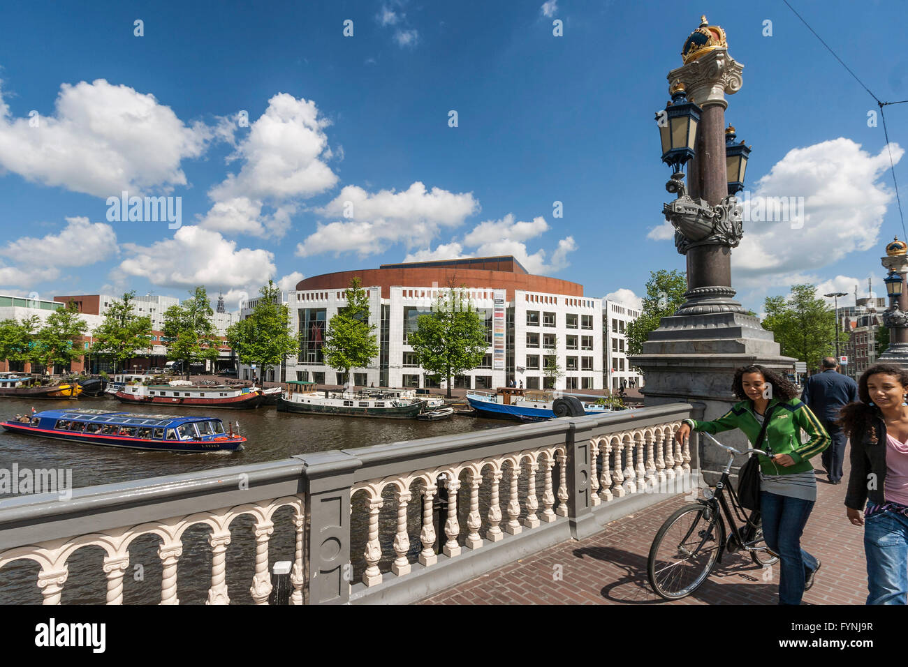 Opera House, Canal Boats, girls with bicycle,  Amsterdam, Netherlands Stock Photo