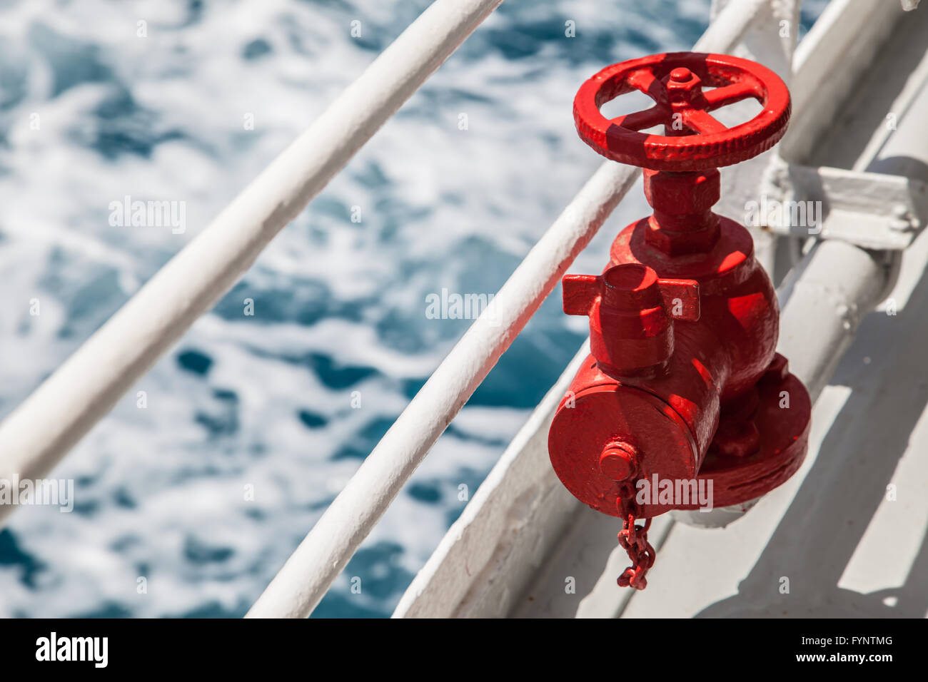 Red fire extinguisher with pipe connector on a boat with waves Stock Photo