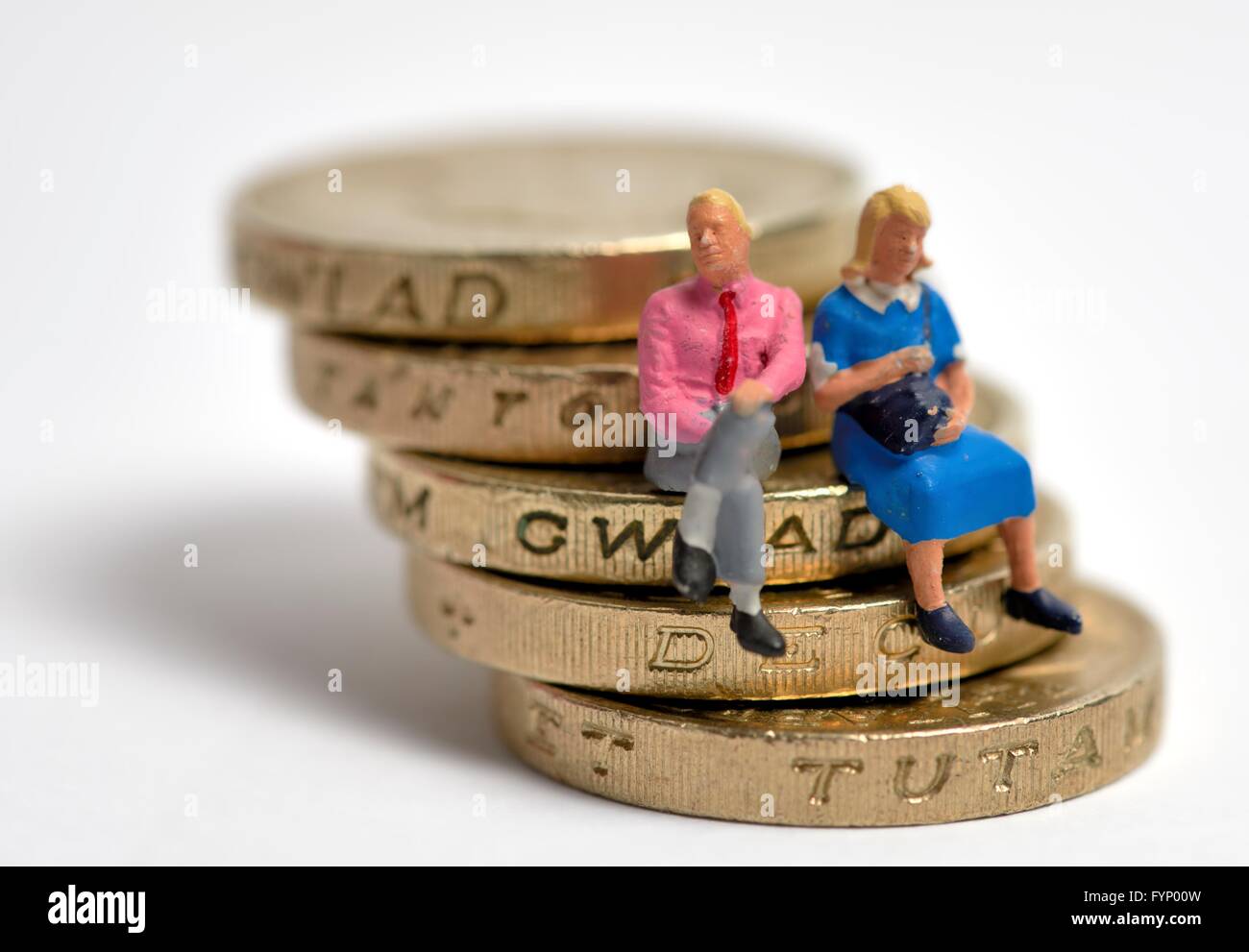 Miniature married couple sitting on a stack of one pound coins Stock Photo