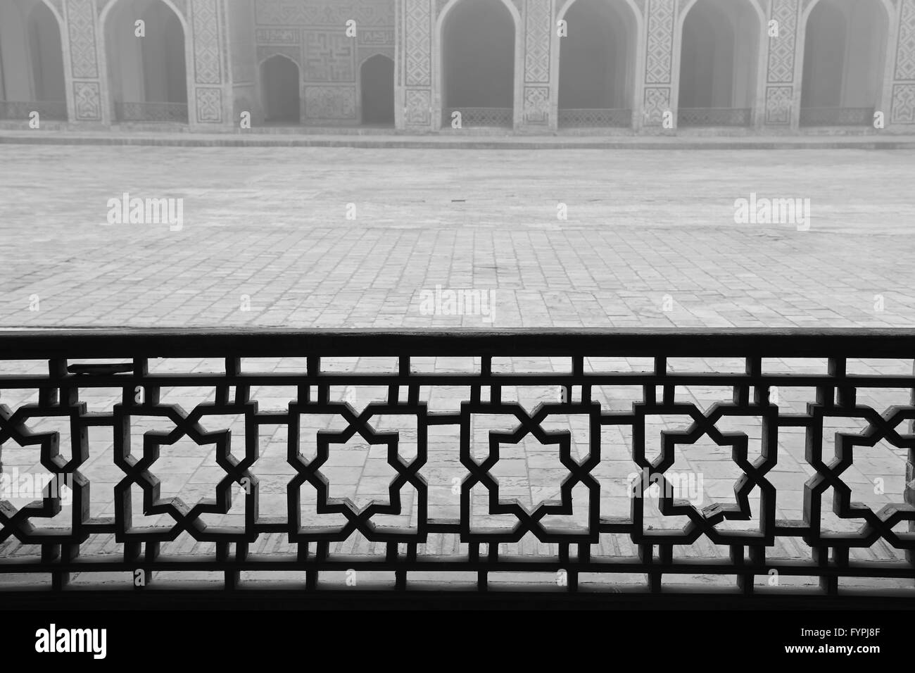 Wood railings separate the side aisles of the Kalon Mosque from its central courtyard.  Bukhara, Uzbekistan. Stock Photo