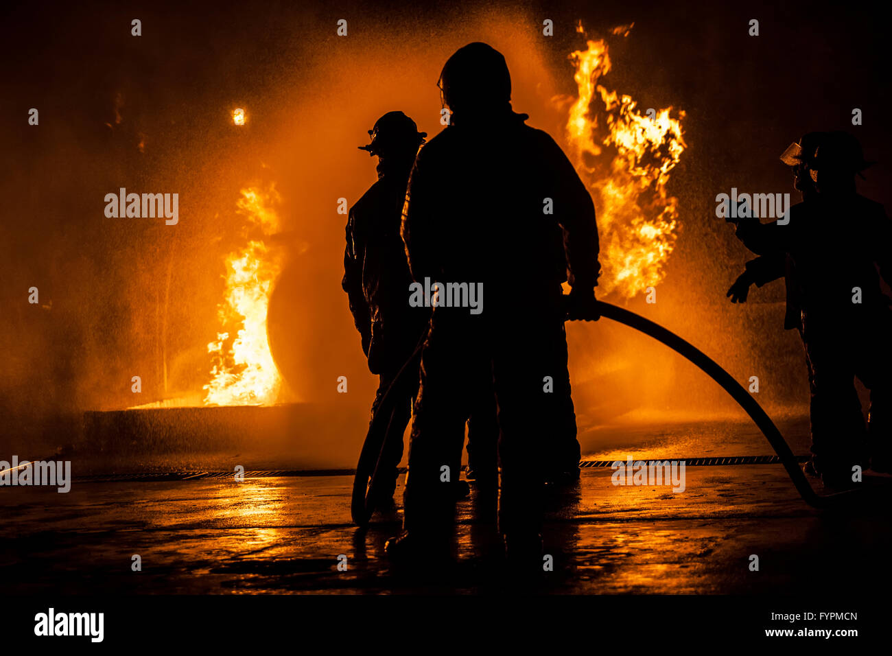 Firefighters standing in a line fighting a fire Stock Photo
